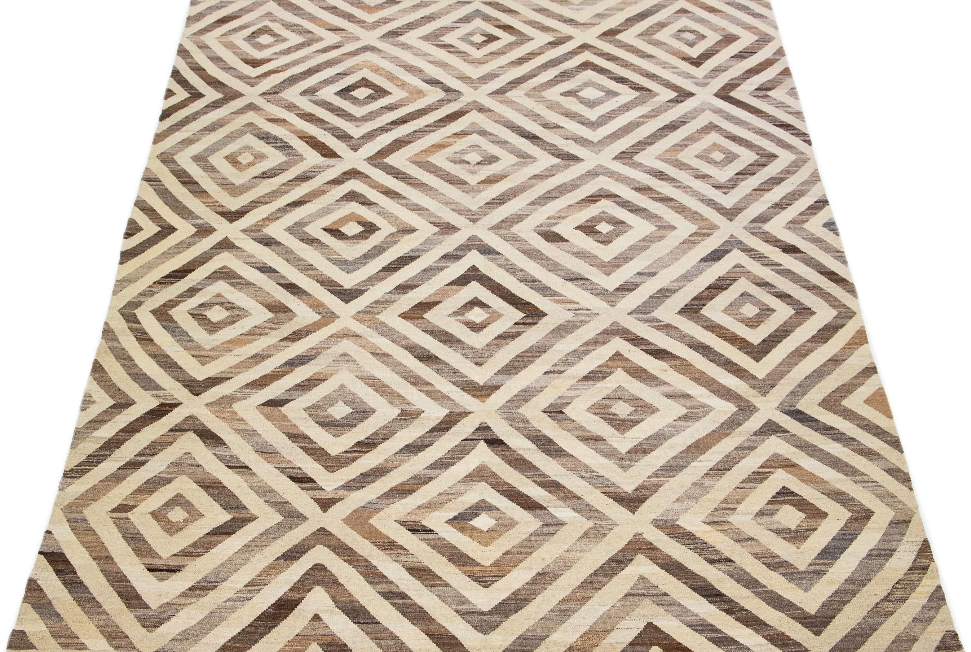 Beautiful Modern Kilim hand knotted wool rug with a geometric abstract design on a beige field and brown accents throughout the piece.

This rug measures 9'2