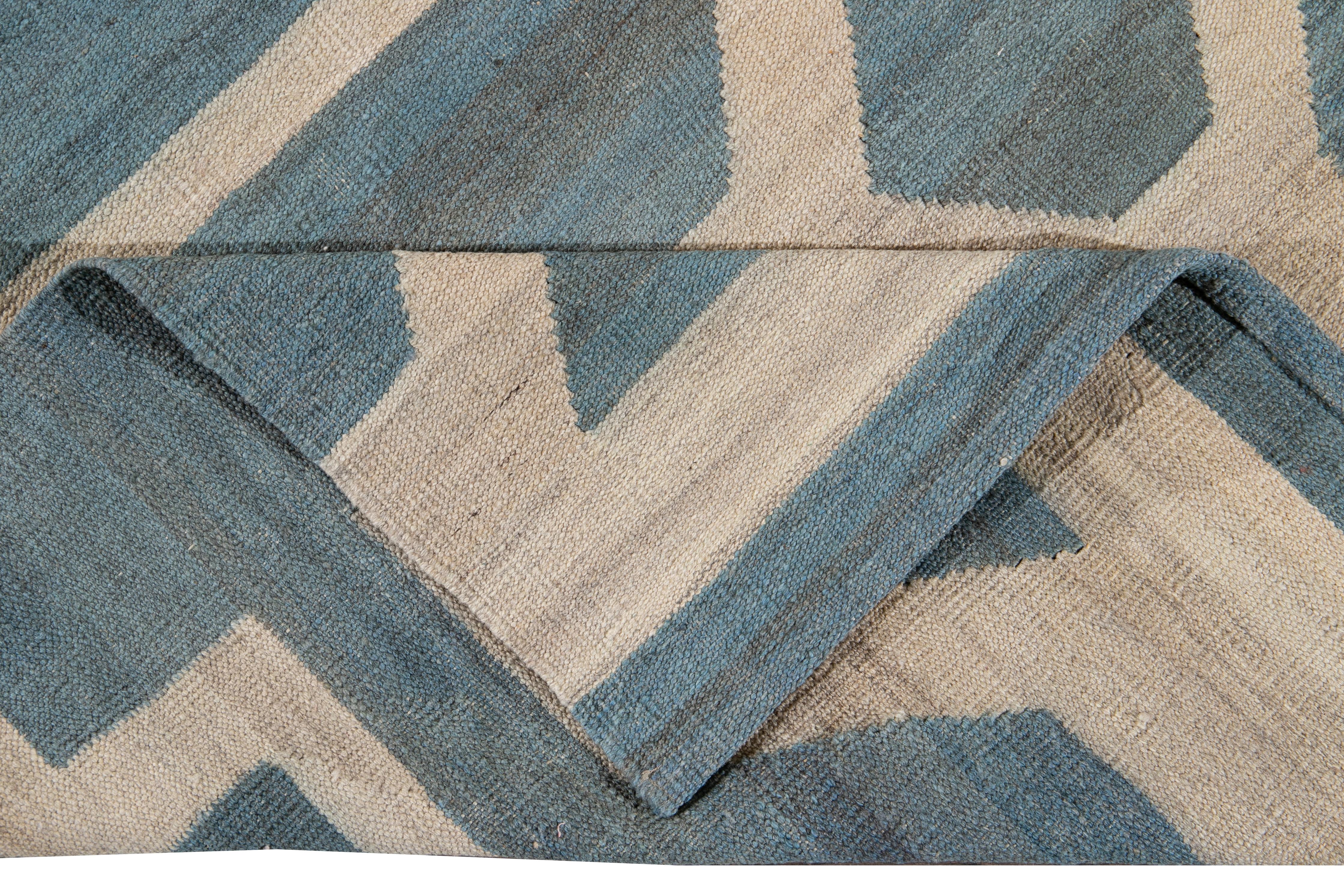 Schöner moderner flachgewebter Kilim-Teppich aus handgefertigter Wolle mit blauem Feld. Dieser Kelim-Teppich hat elfenbeinfarbene und braune Akzente in einem wunderschönen geometrischen expressionistischen Design.

Dieser Teppich misst: 9'11