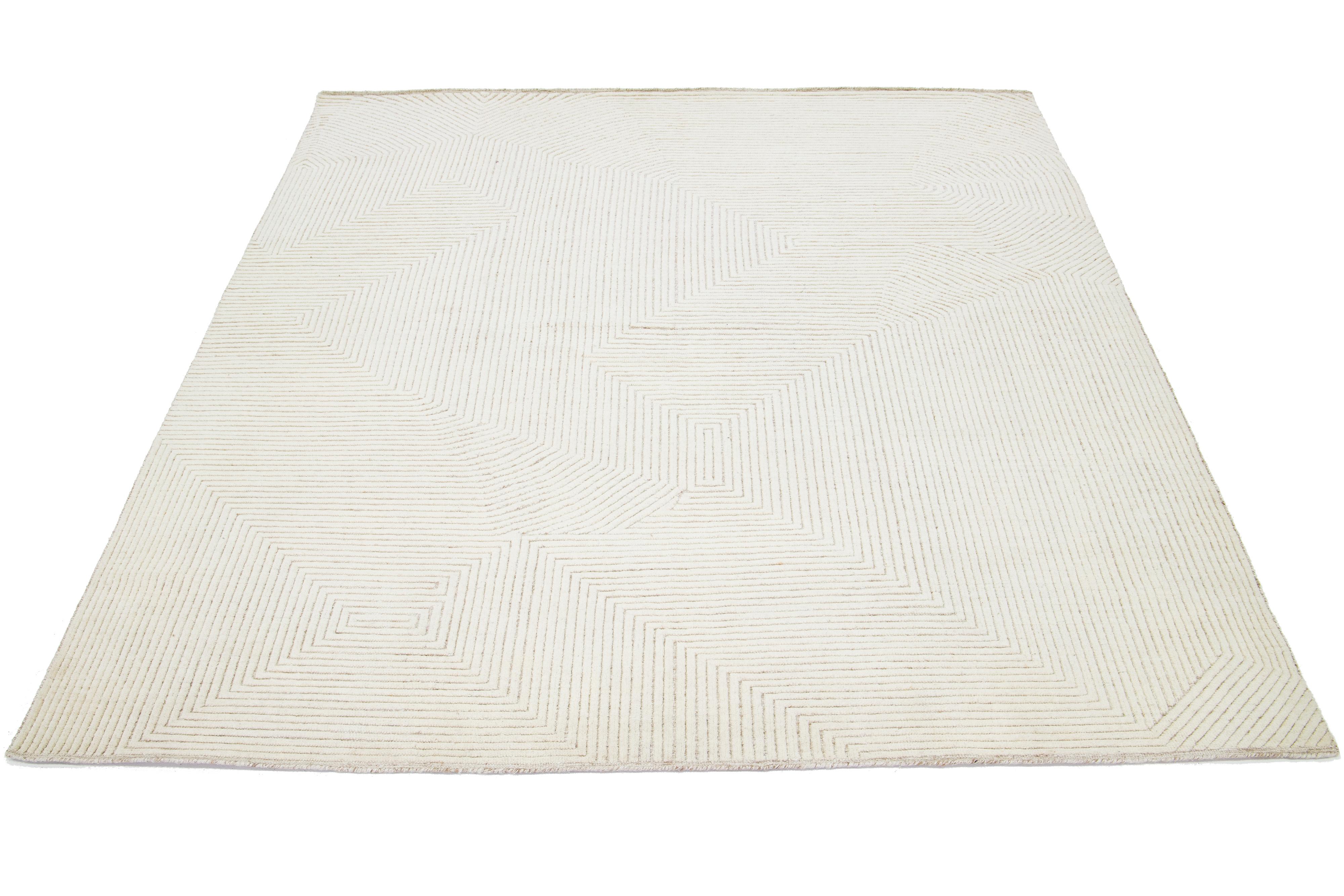 This modern Moroccan rug is hand-knotted from wool and showcases an elegant geometric design in exquisite shades of ivory.

This rug measures 8' x 10'1