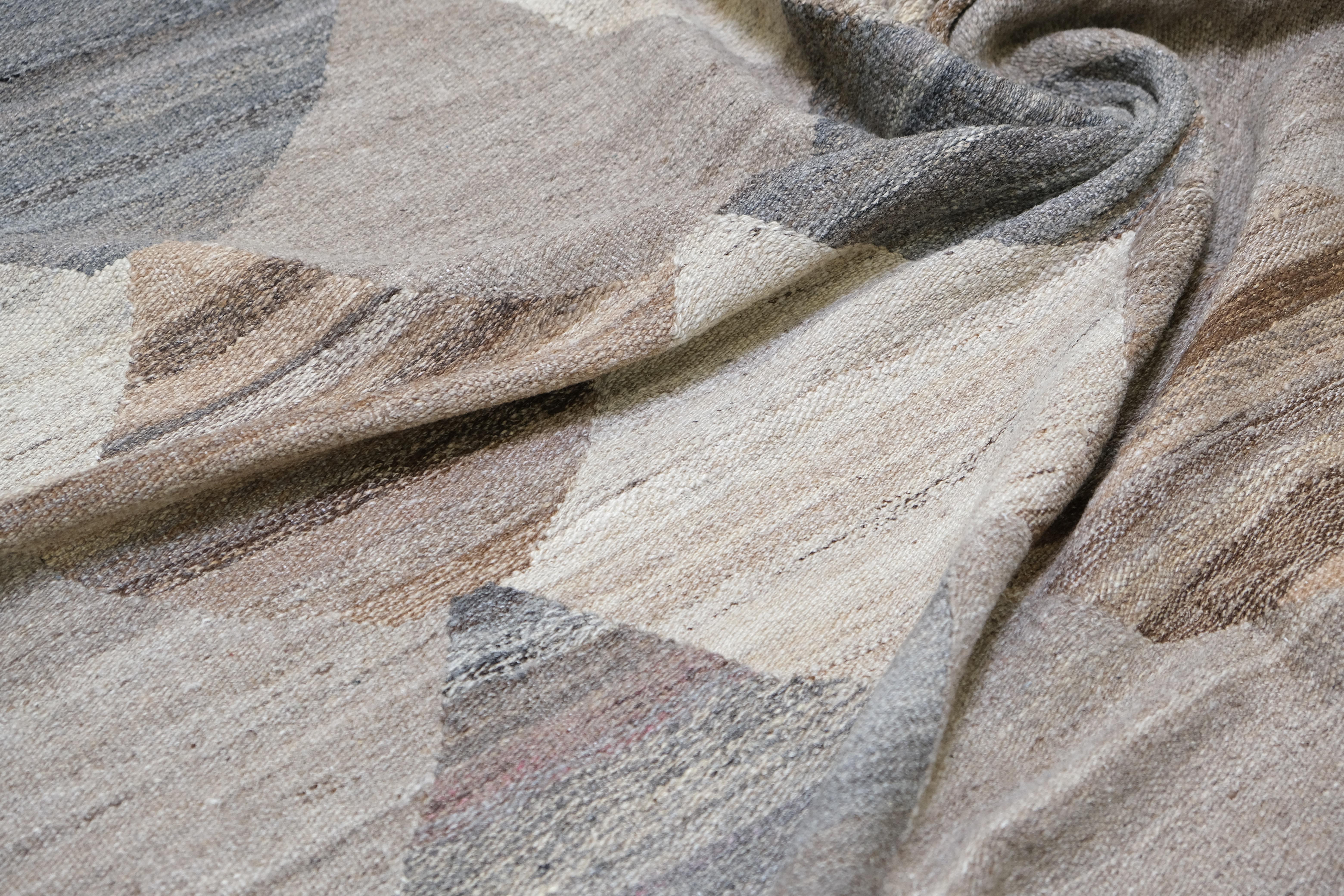 Dieser handgewebte Kelimteppich ist ein modernes textiles Statement, das in jahrhundertealten Flachgewebe-Traditionen wurzelt. Der Teppich zeichnet sich durch ein kühnes und fesselndes geometrisches Muster aus, das sich aus ineinandergreifenden
