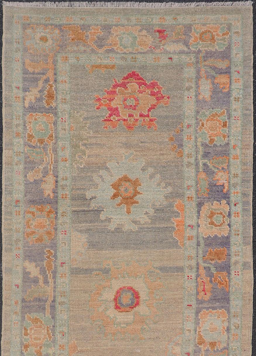 Geometric Oushak rug with tan, pink, orange, blue, neutral color palette and all-over flower design, Keivan Woven Arts/rug AFG-36119, country of origin / type: Afghanistan / Oushak

This traditional Oushak rug features a neutral color background