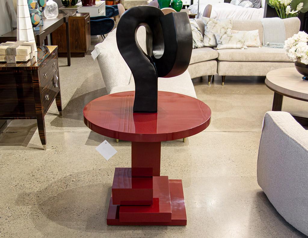 Moderner geometrischer runder Beistelltisch in rubinroter Lackierung. Dieses atemberaubende Möbelstück verfügt über einen einzigartigen geometrischen Würfelsockel, der jedem Raum einen Hauch von moderner Eleganz verleiht. Der Sockel ist fachmännisch