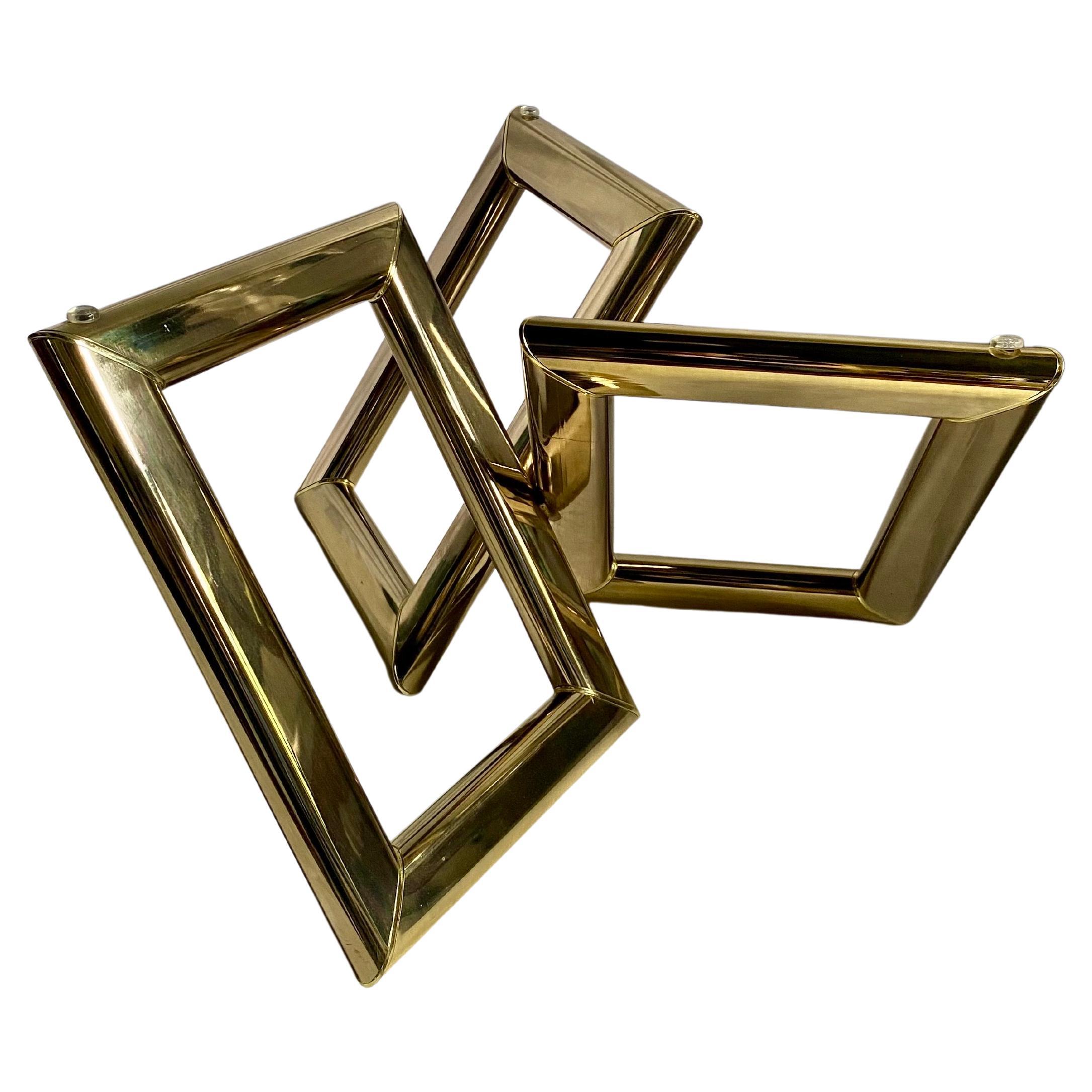 Sculptural Mid Century Modern geometric form coffee table, circa 1970's.  Three interlocking polished gold brass rectangular links support a removable round glass top.  In the style of Karl Springer. 