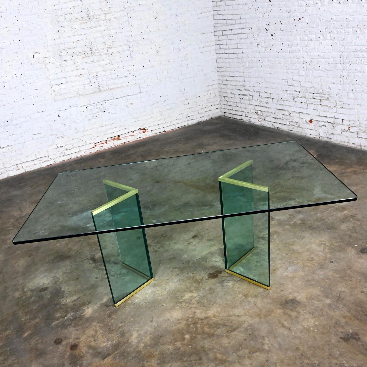 Magnifique table de salle à manger moderne en verre à double piédestal avec plateau en verre rectangle de ¾ de pouce et canaux en forme de V en laiton brossé attribués à The Pace Collection. Cette pièce a été attribuée sur la base de recherches