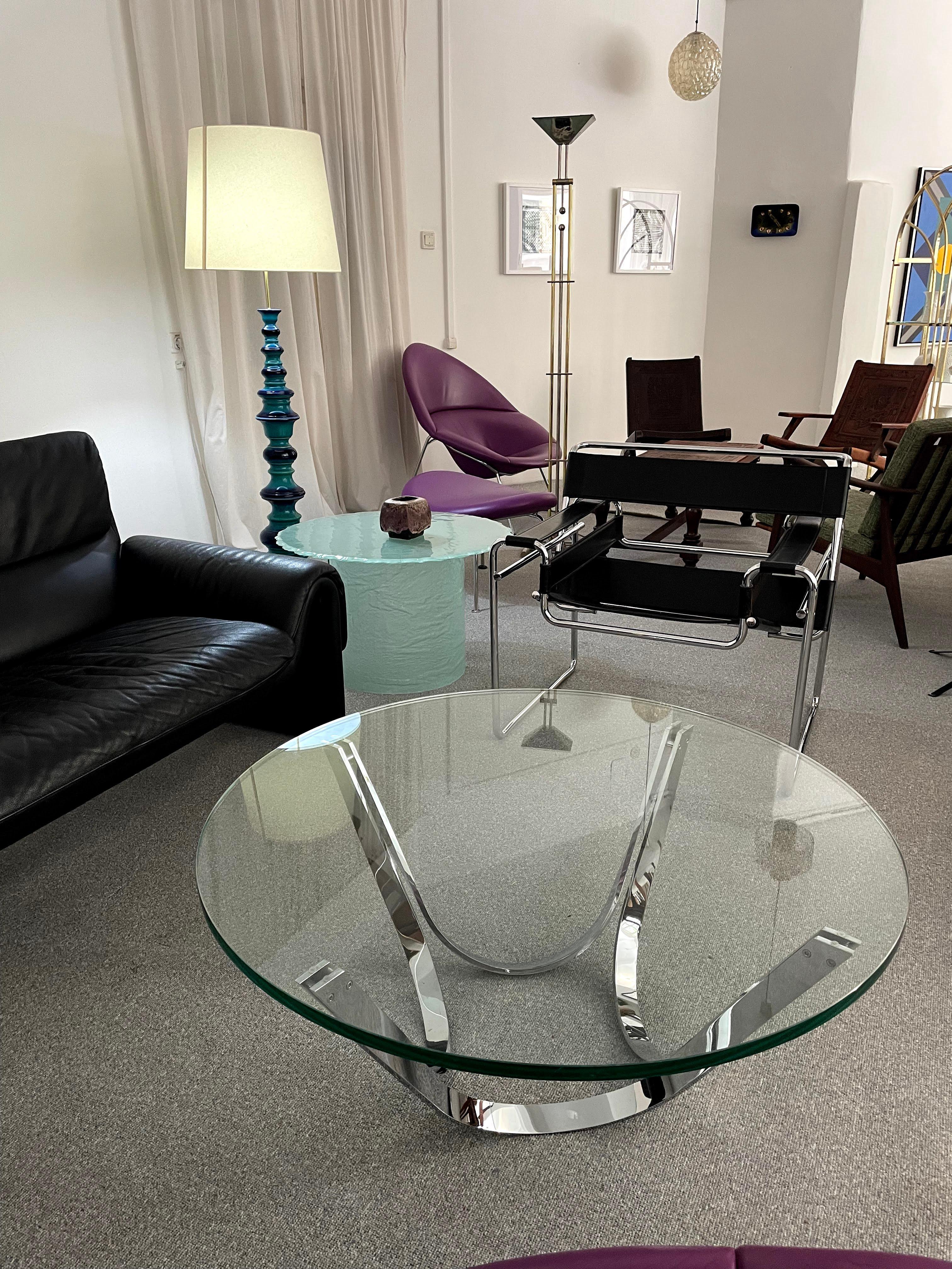 This table was designed by Roger Sprunger in the 1960s for Dunbar Furniture (United States). The table features a polished steel frame which can be flipped over. The table is photographed with a 99 cm diameter glass top (thickness 20 mm).
