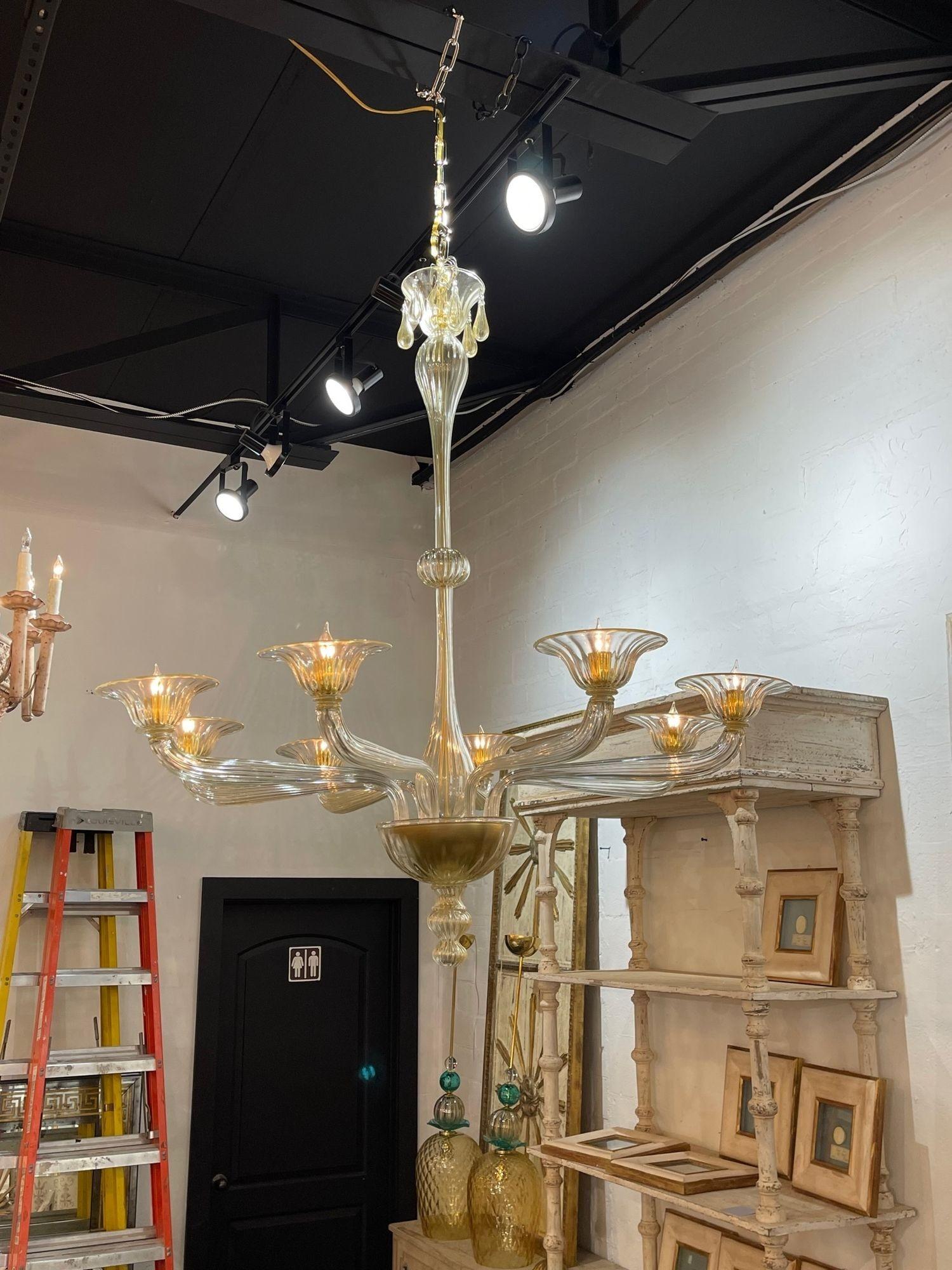 Stylish modern Murano glass chandelier with 8 lights. Featuring beautiful glistening gold glass and decorative arms and base. Makes an impressive statement!.
