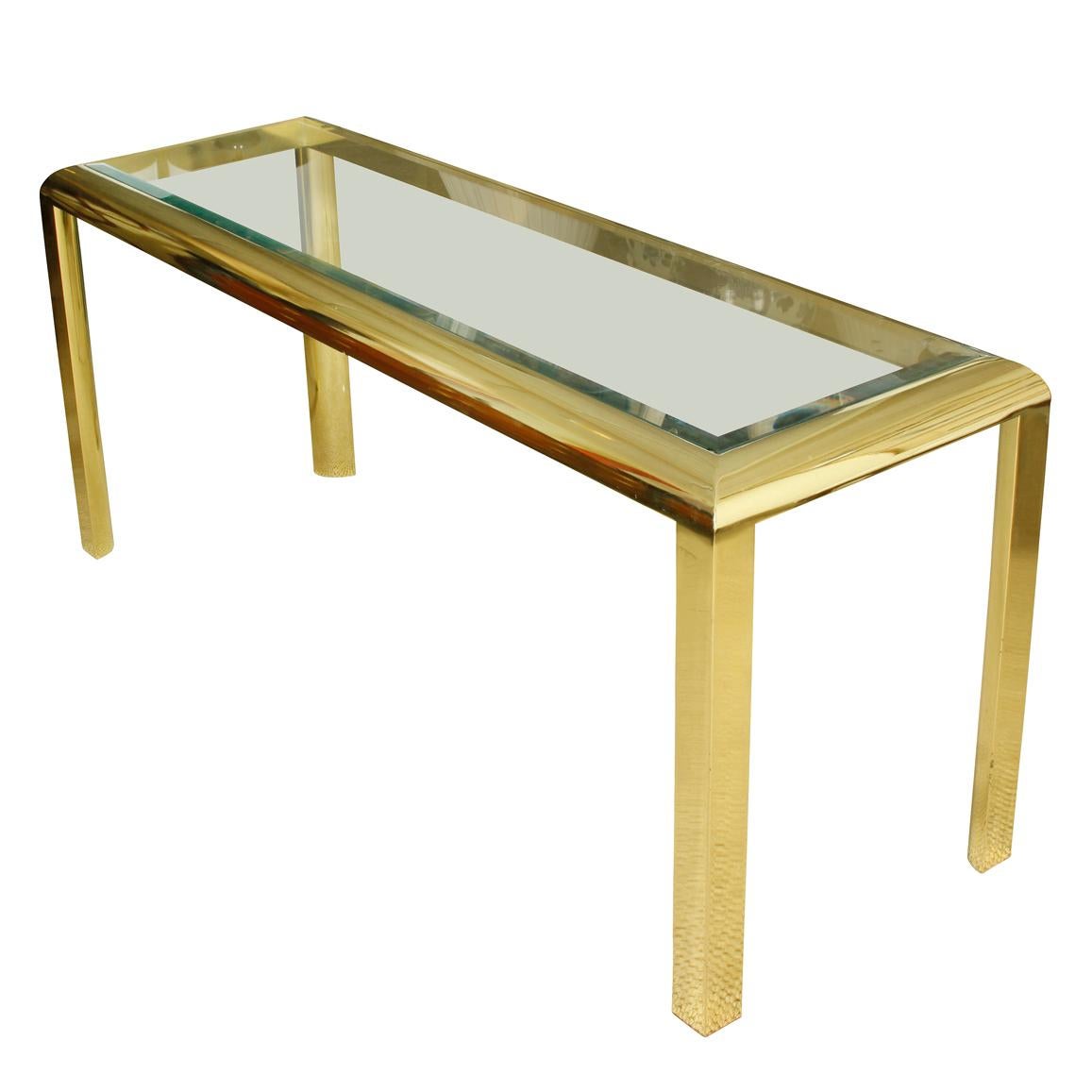 A contemporary styled sleek gold tone console table with glass top. A vintage table with a streamlined, modern look.