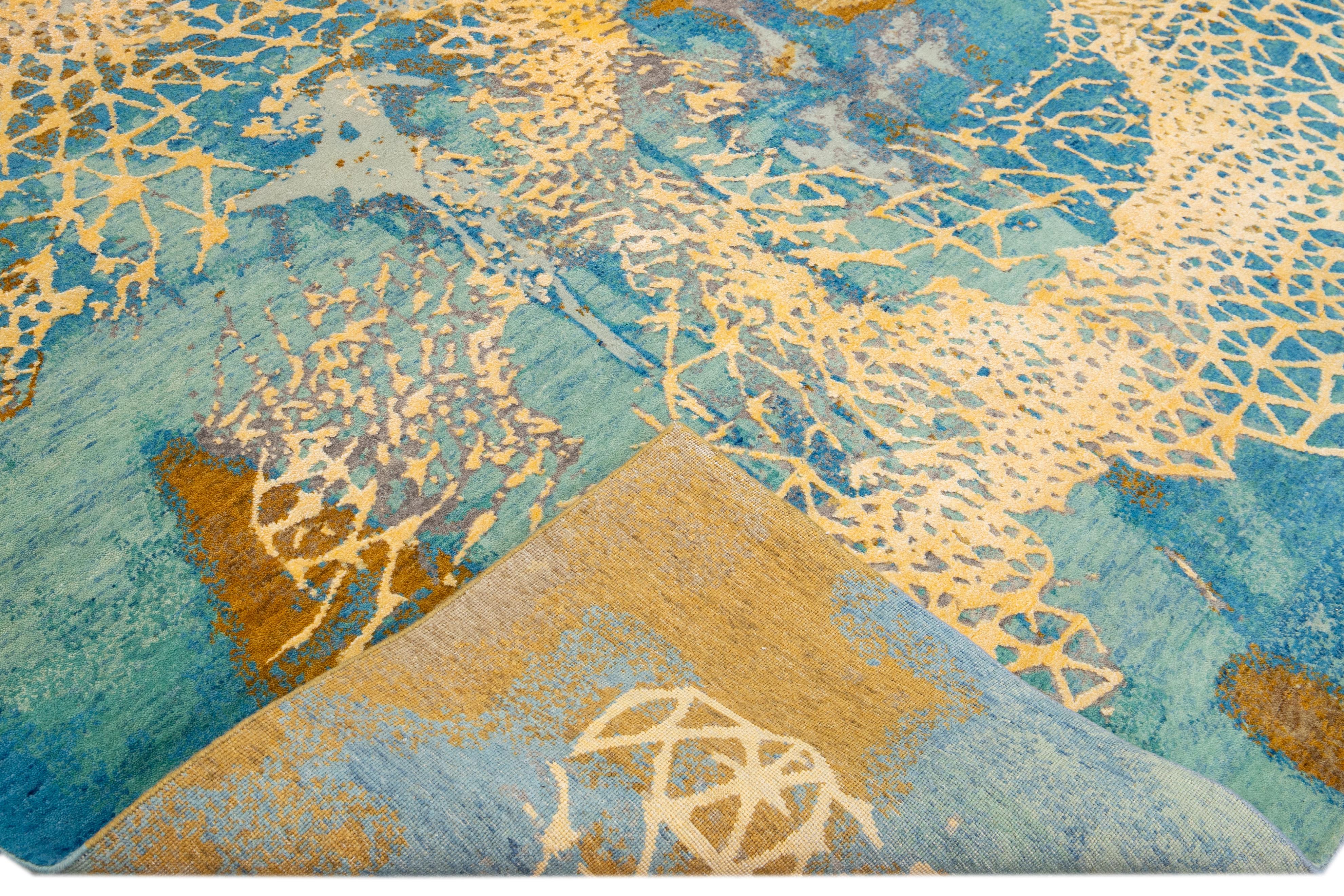 Beautiful modern Indian hand-knotted wool and silk rug with a golden-teal field. This Modern rug has red, gray, and beige accents a gorgeous layout Abstract coastal design.

This rug measures: 9'1