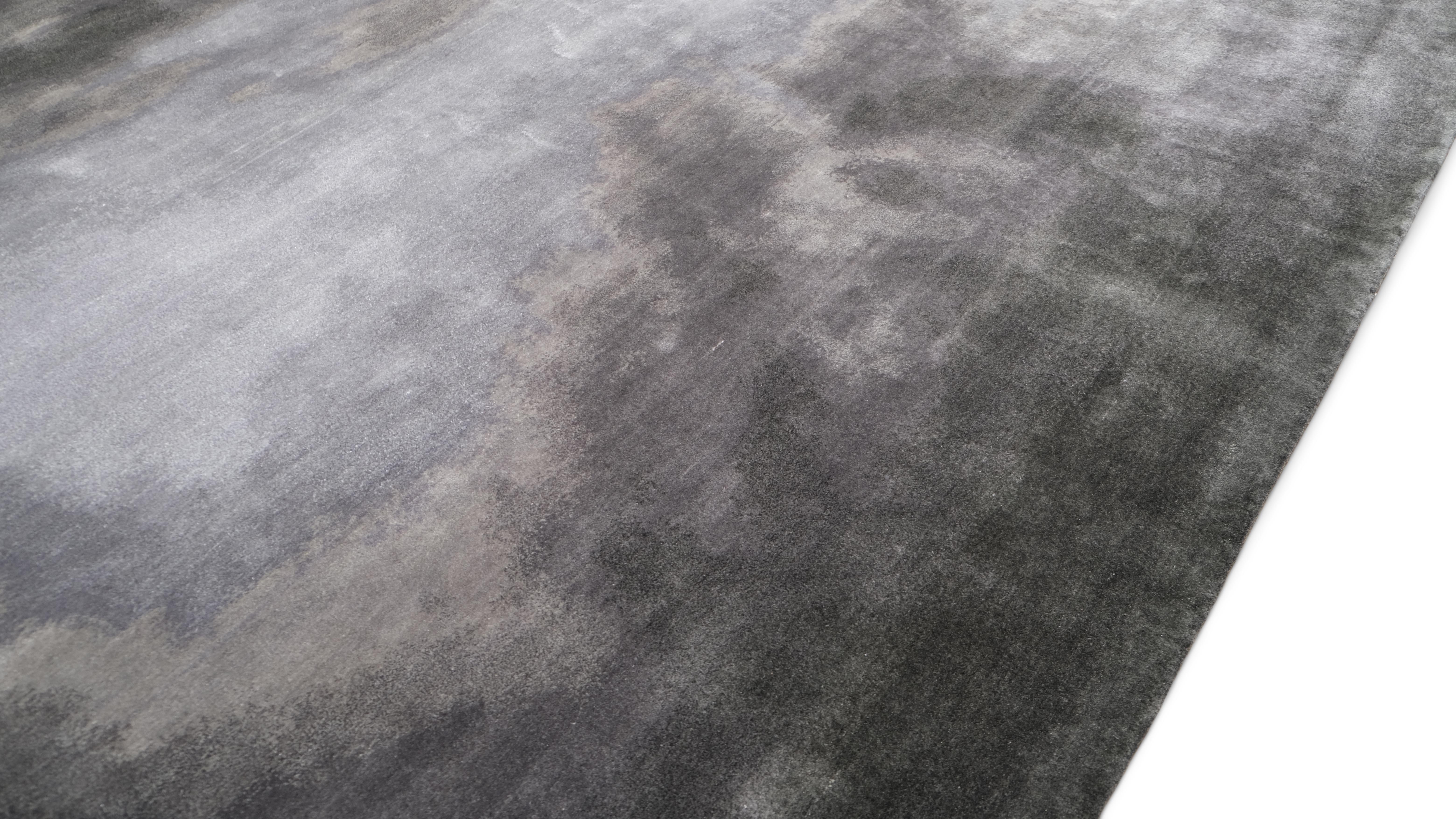 Dieser handgeknüpfte Wollteppich ist ein eindrucksvolles Beispiel für moderne Kunst und außergewöhnliche Handwerkskunst. Mit seinem abstrakten, wolkenähnlichen Muster in verschiedenen Grau- und Kohleschattierungen erinnert dieser moderne Teppich an