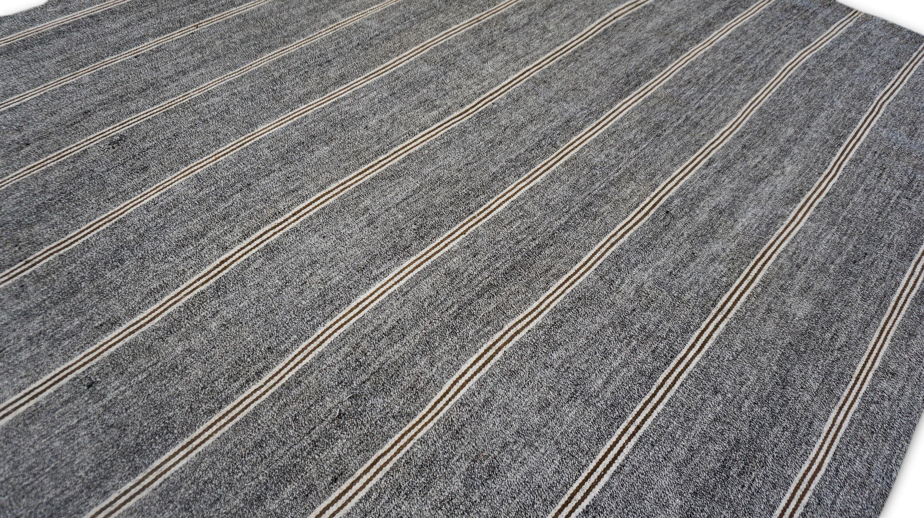 Tessuto con autenticità grezza e fascino duraturo, questo kilim turco vintage è realizzato in canapa naturale filata a mano e presenta un motivo a righe minimalista che evoca equilibrio e semplicità. L'alternanza di linee color tortora, avorio e