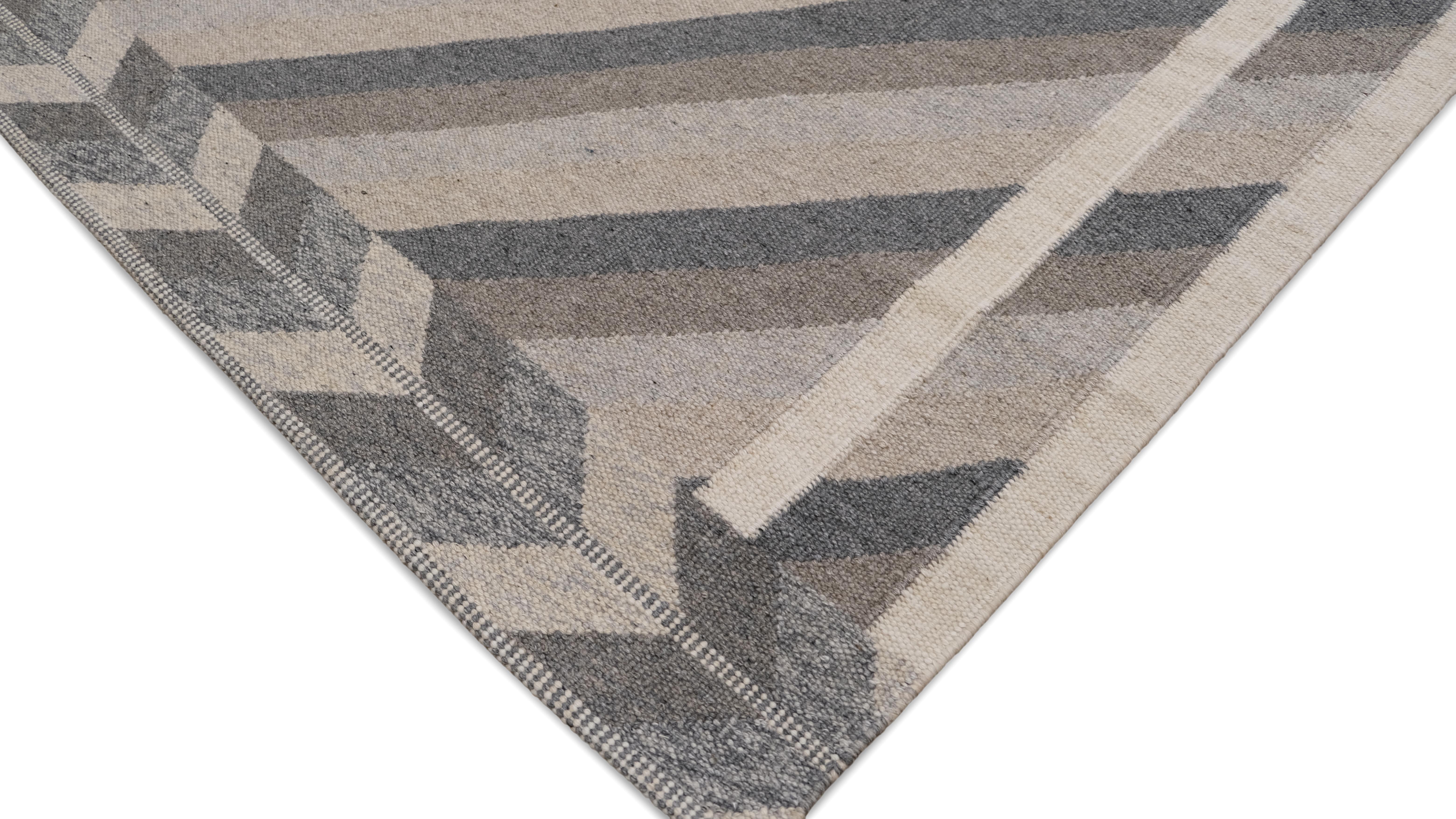 Dieser handgeknüpfte Wollteppich zeigt ein auffälliges diagonales Streifenmuster, das von einer geometrischen Chevron-Bordüre eingerahmt wird. Die weiche, neutrale Farbpalette aus Grau, Beige und Elfenbein erhöht seine Vielseitigkeit und macht ihn