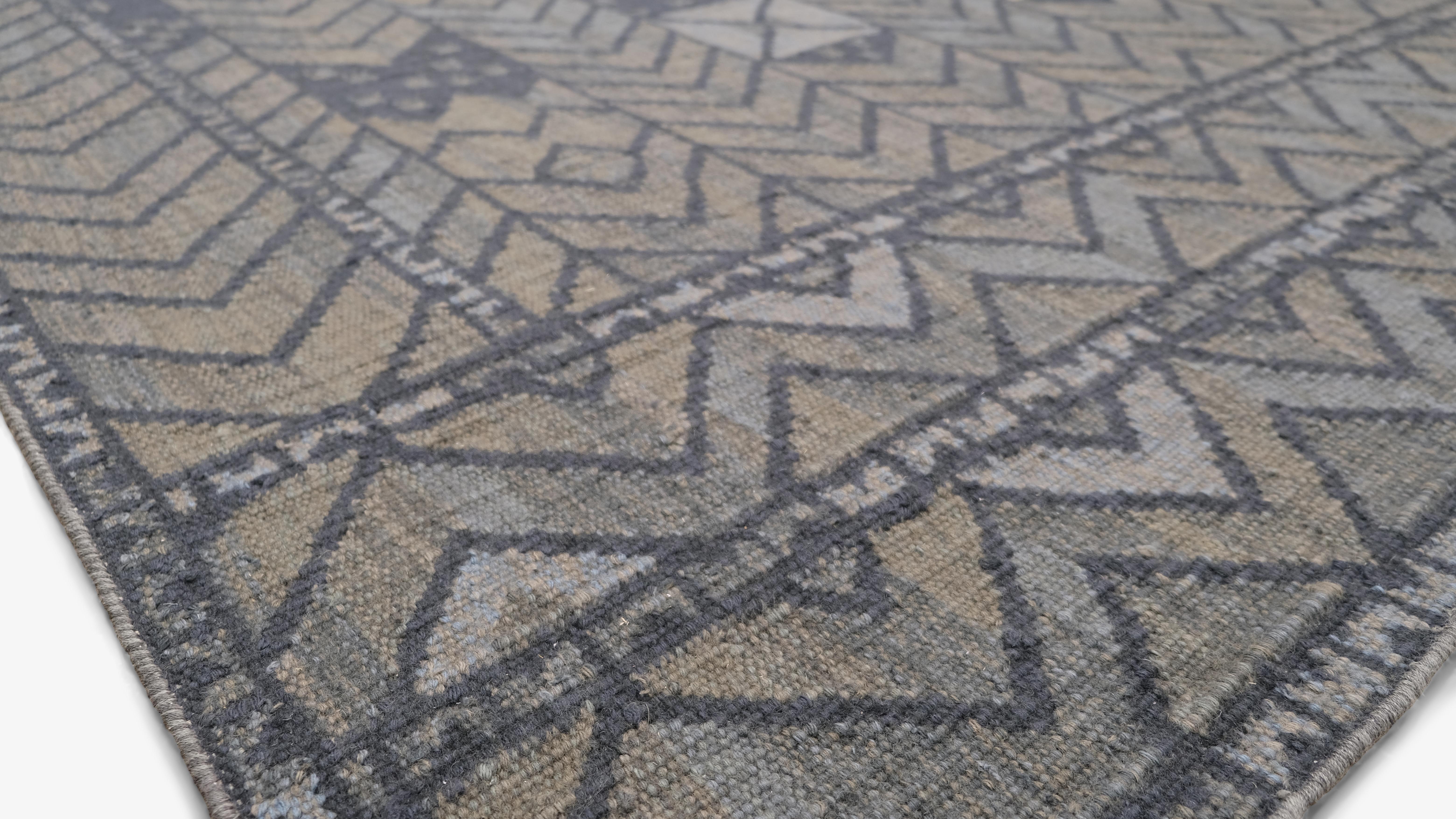 Dieser handgeknüpfte Wollteppich zeigt ein atemberaubendes, vom Stammesleben inspiriertes, geometrisches Design, das traditionelle Motive mit einer zeitgenössischen Ästhetik verbindet. Das verschlungene Muster mit Zickzacklinien, abstrakten