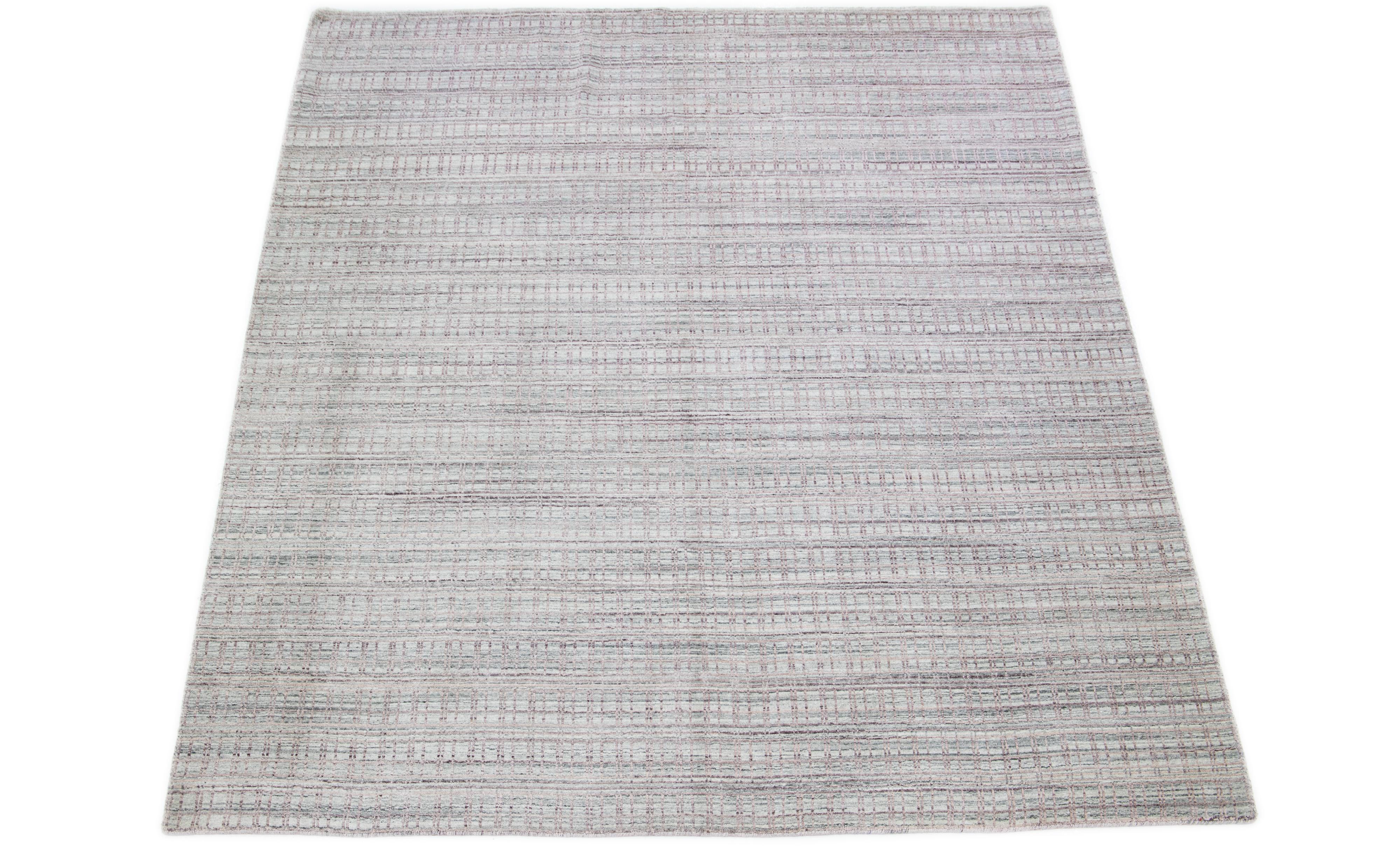 This rug, made from wool and silk, displays an enthralling geometric pattern in pink, expertly embodied over a seductive light gray base tone. 

This rug measures 8'3