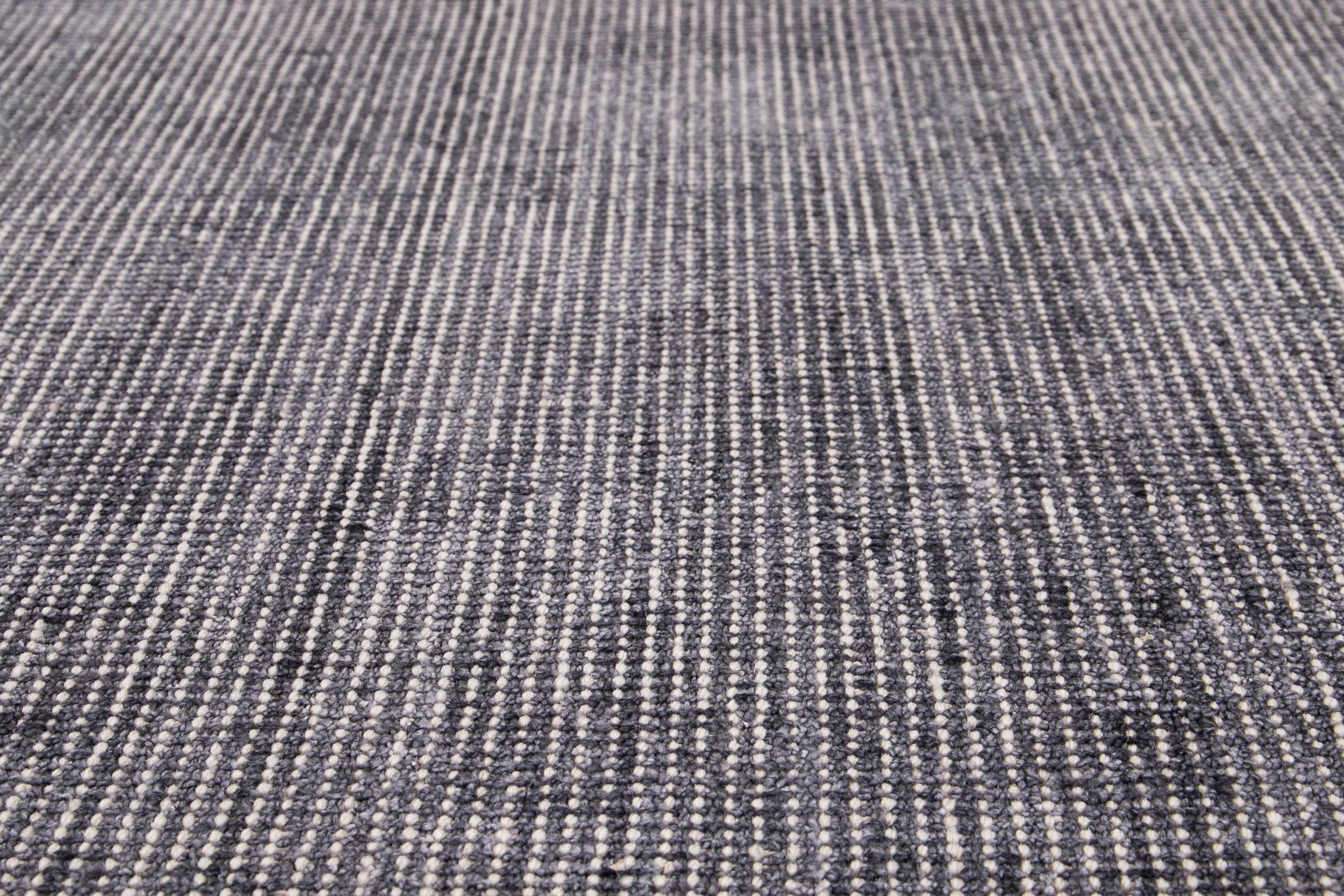Der wunderschöne handgefertigte Teppich Apadana aus Indien besteht aus einer Kombination von Bambus-, Seiden- und Wollmaterialien mit einem wunderschönen grauen Feld und einer blaugrünen Bordüre. Dieser Teppich gehört zur Groove Collection und