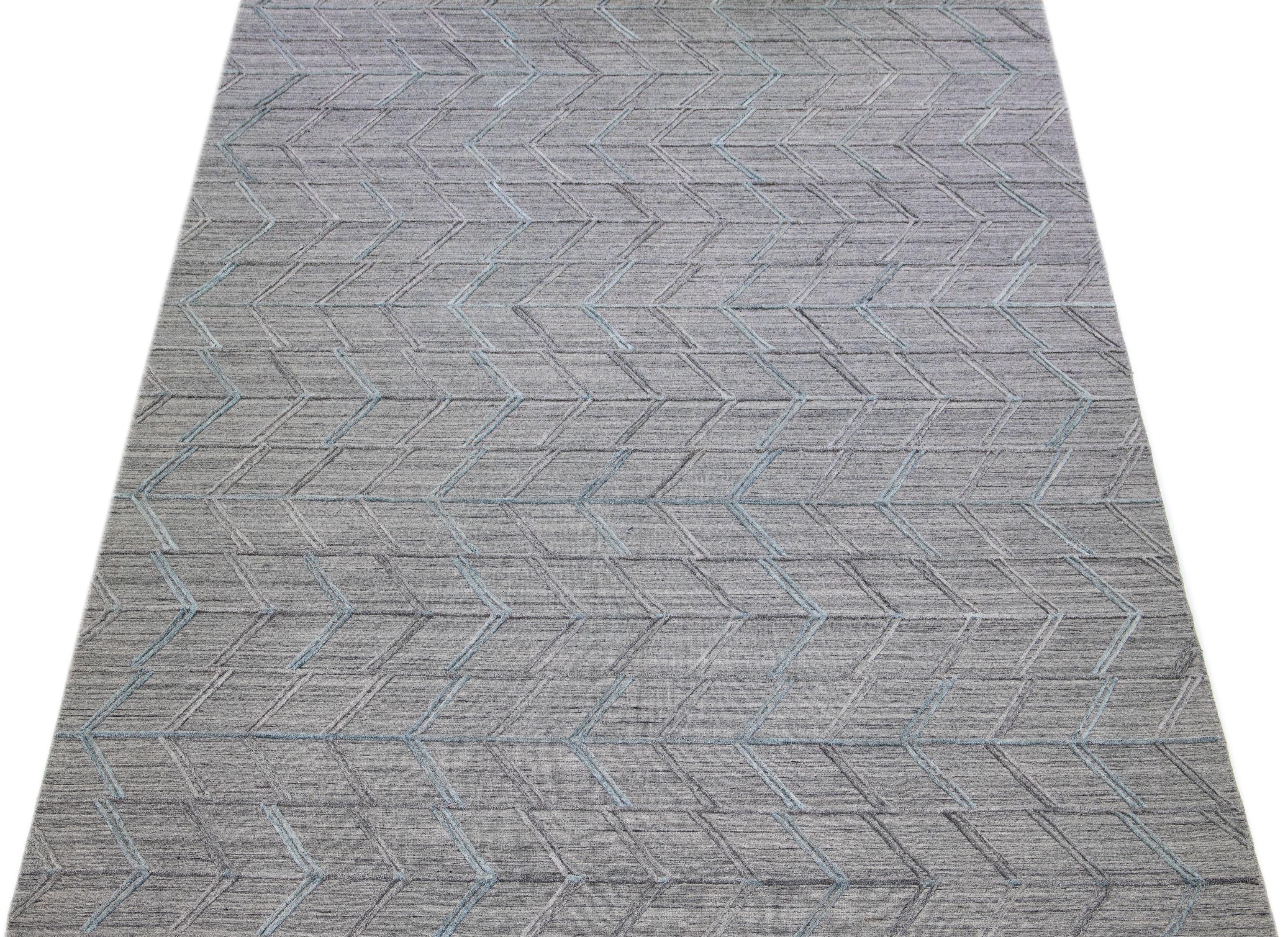 Erleben Sie die Schönheit eines modernen indischen Flachgewebe-Teppichs aus handgeknüpfter Wolle mit einem raffinierten grauen Feld. Zu seinem eleganten Charme trägt das strukturierte und anmutige hellblaue geometrische Muster bei, das sich durch