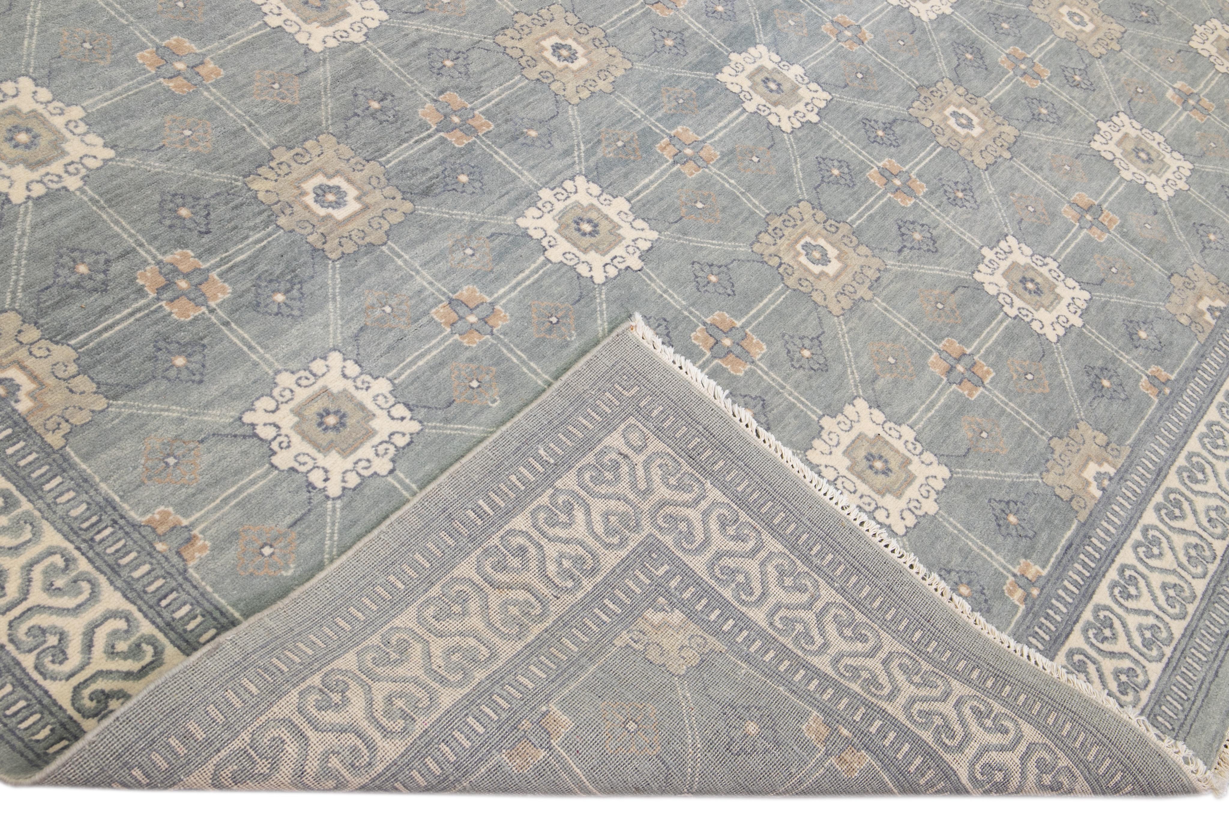 Beautiful Modern Khotan style hand-knotted wool gray field. This Khotan-style rug has a beautifully designed frame and accent of ivory, beige, and blue in a gorgeous all-over geometric floral design.

This rug measures 11' 10