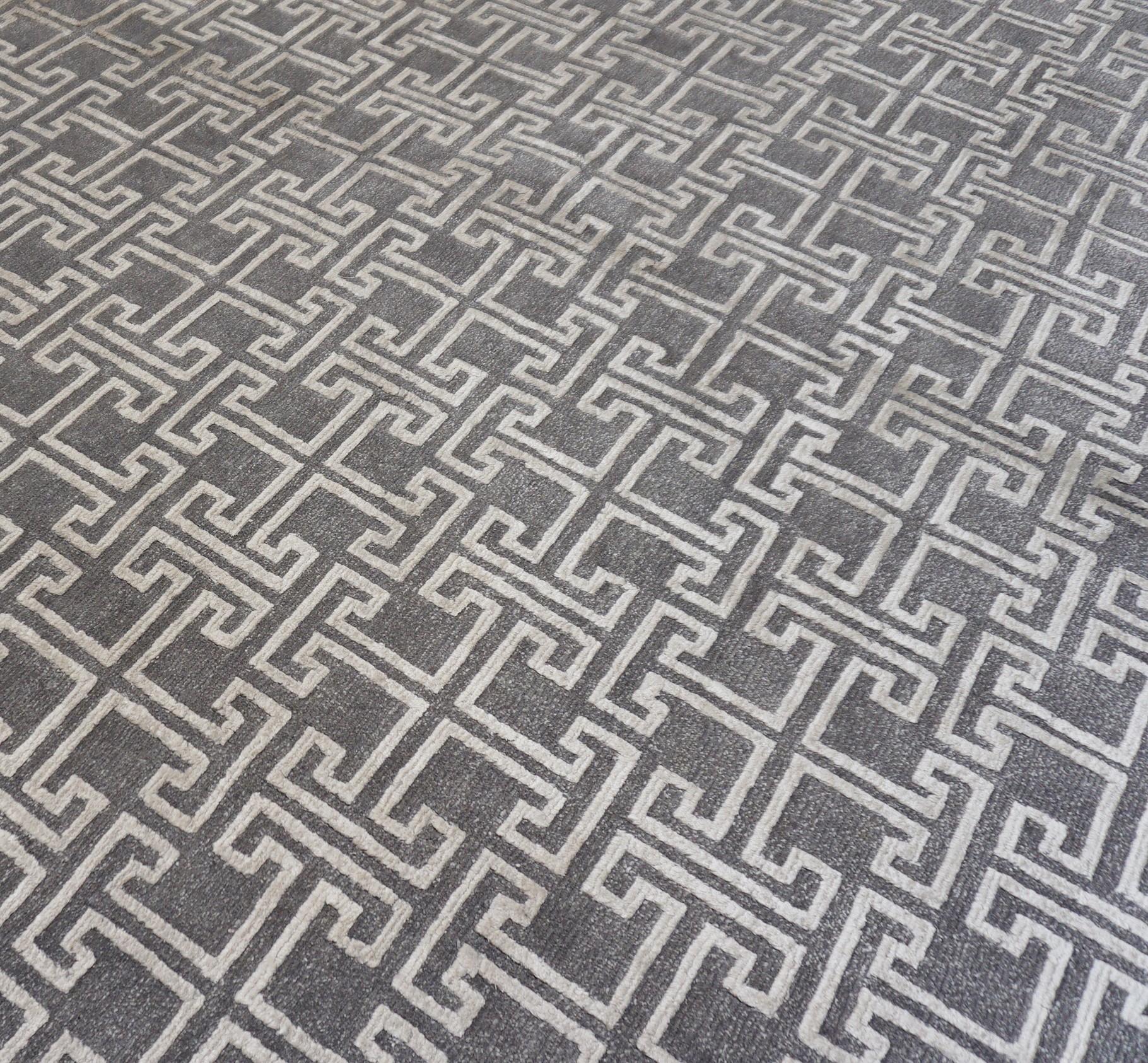 Dieser handgeknüpfte Teppich zeigt ein auffälliges geometrisches Labyrinthmuster und wurde fachmännisch aus einer luxuriösen Mischung aus Wolle und Bambus gefertigt. Das zeitgenössische Design zeichnet sich durch ein rhythmisches,