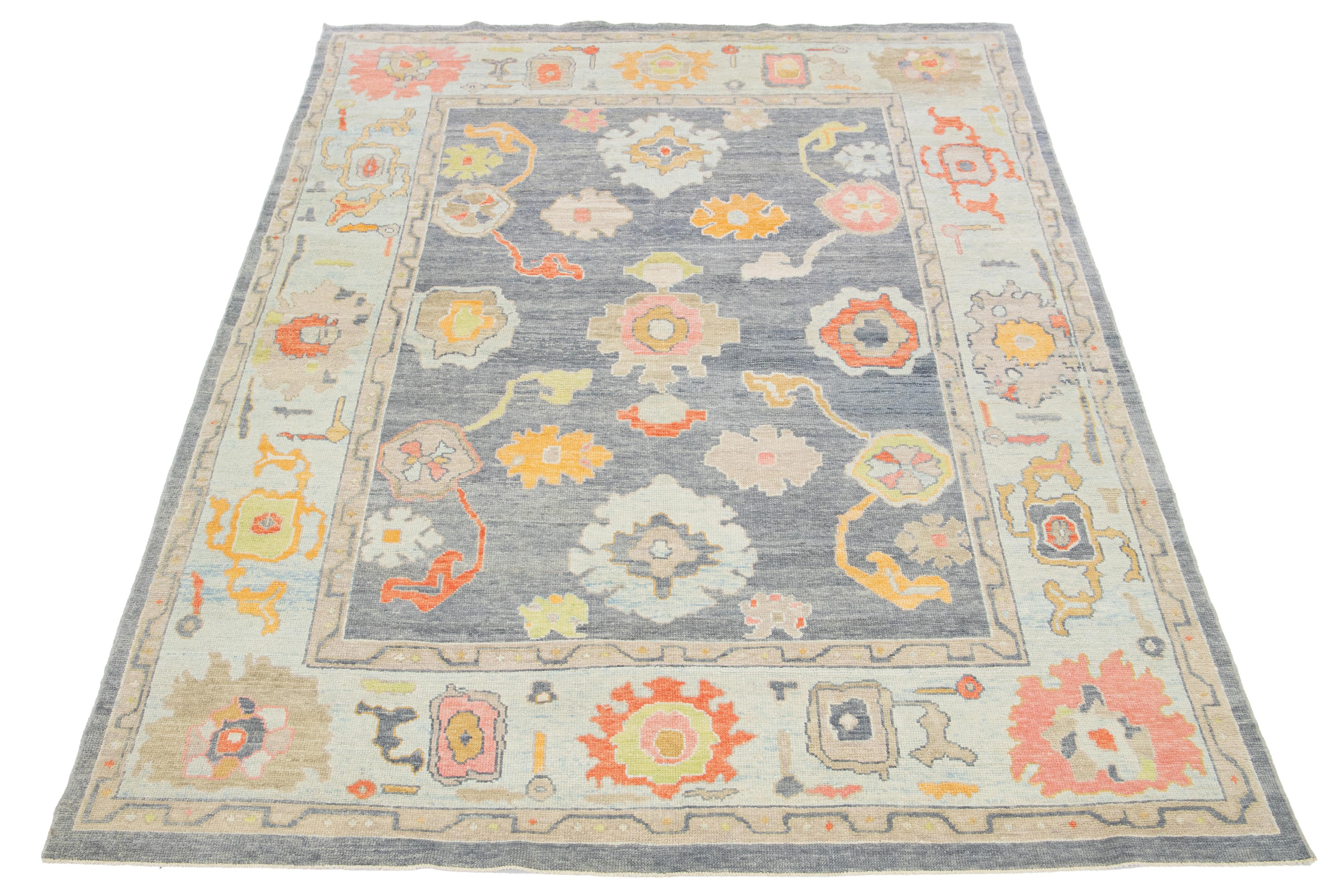 This hand-knotted wool rug is a modern Turkish piece featuring a gray field with a light blue frame and a captivating allover design of multicolor floral patterns.

This rug measures 8'9