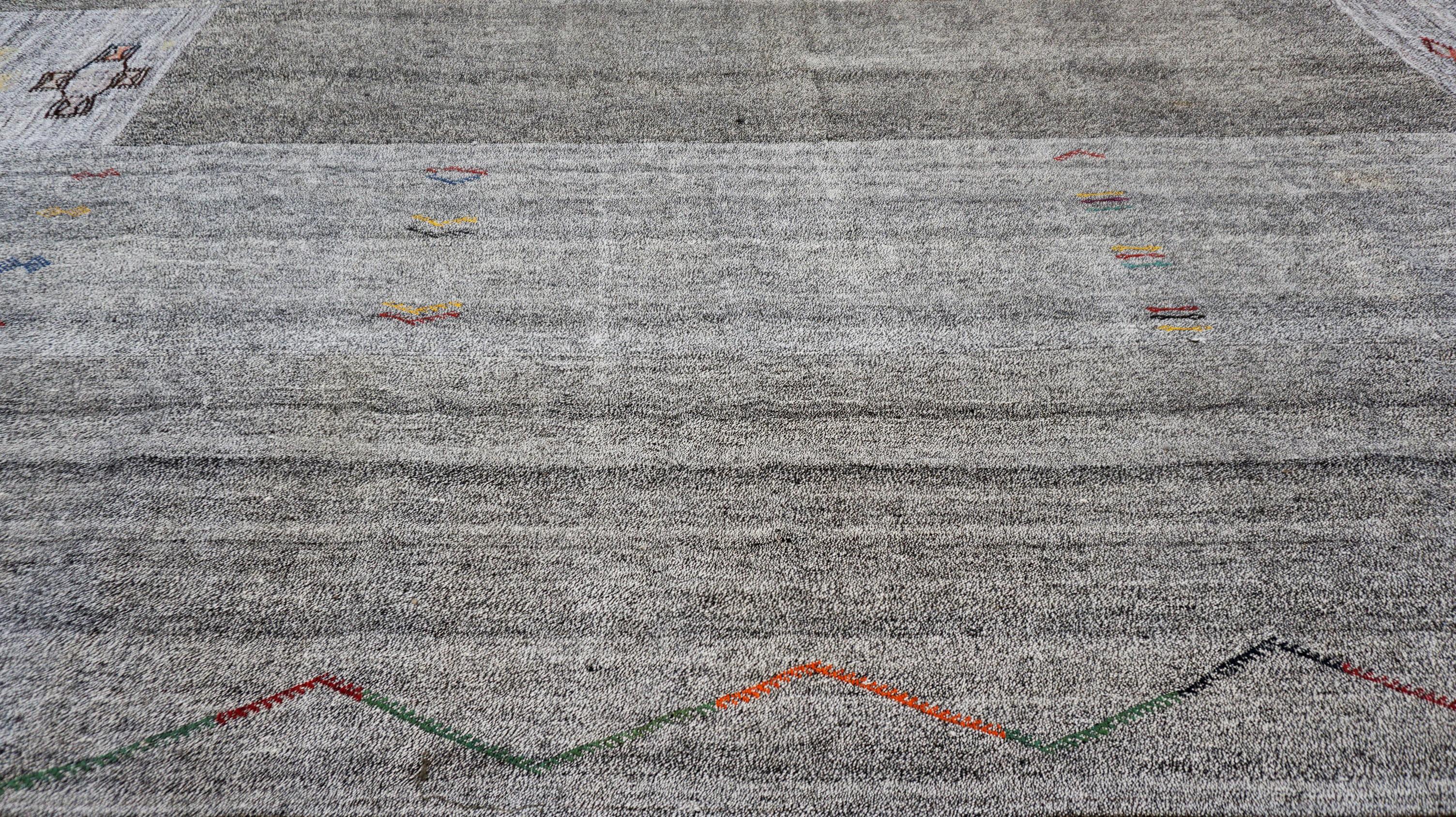 This vintage hand-woven wool and hemp flatweave rug features a subtle minimalist design with a rich cultural narrative. Woven using undyed natural wool, the rug displays softly striated fields of warm and cool grays, creating a soothing and organic