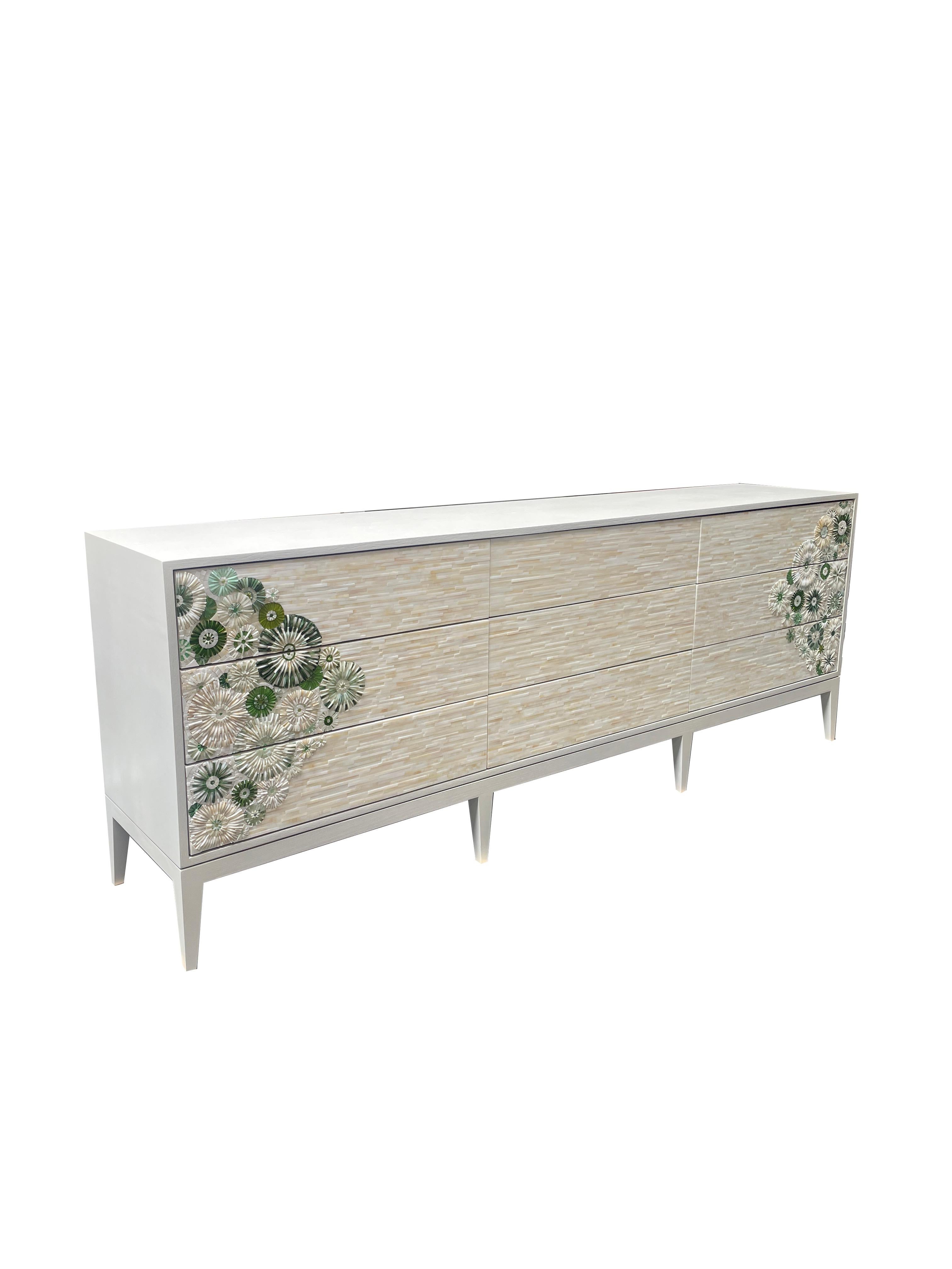 The Modern Milano Chest of 9 Drawers by Ercole home has a 9 drawer front, with a White Wash finish on oak. The touch-latch drawer's feature fronts in hand-cut glass mosaic, in shades of green and ivory, and fields of Ivory mosaic stripe. 

Made in