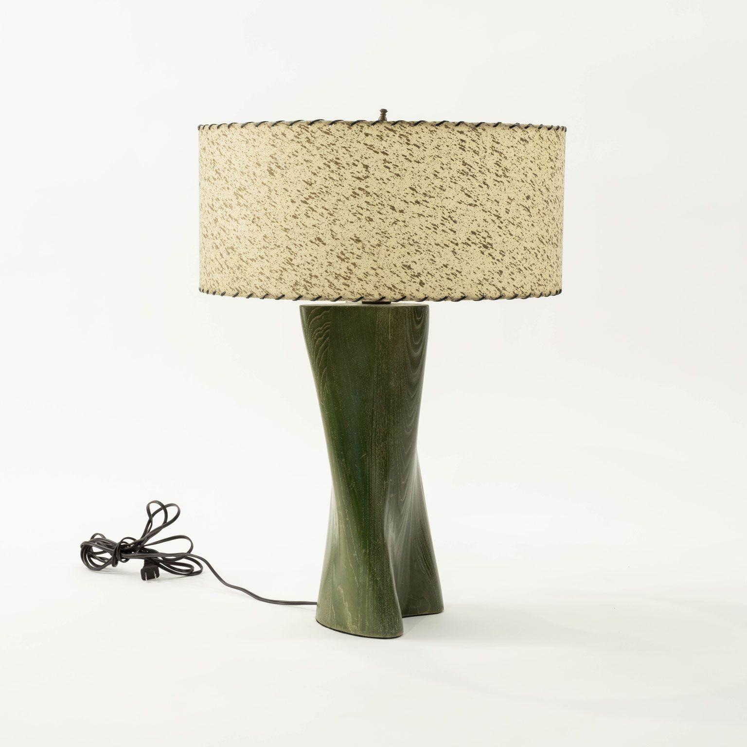 Lampe de table moderne en bois sculpté teinté en vert, circa 1960-1979. Câblée pour une utilisation aux États-Unis et comprend un abat-jour à tambour peu profond (les mesures indiquées comprennent l'abat-jour).

Note : Les différences régionales