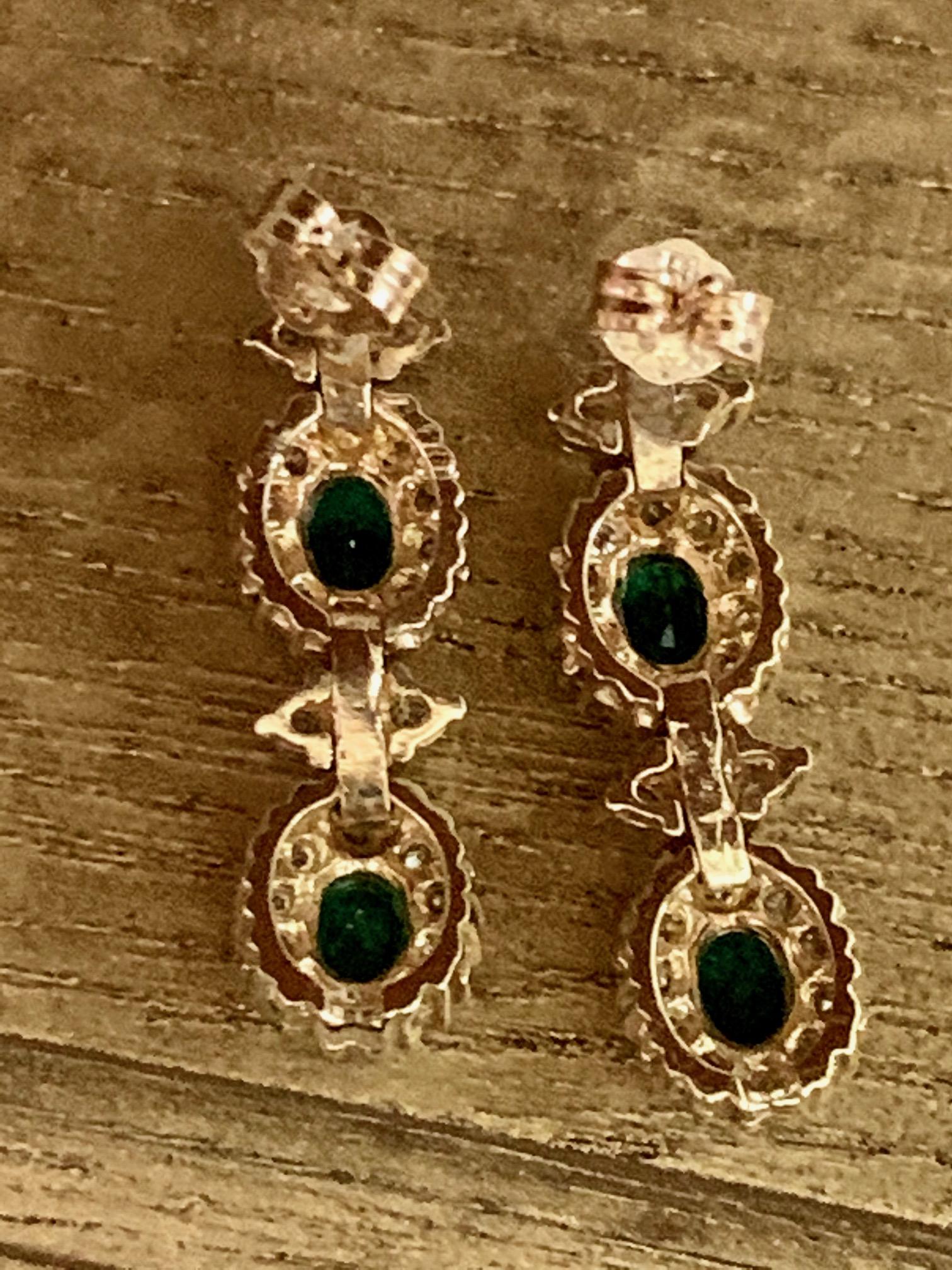 These modern dangle earrings feature four - 5 x 4mm oval green Emeralds. The total estimated weight is 1.60 carats.  There are also 56 2mm brilliant cut Diamonds with a total estimated weight of 1.95 carats.  The average grade is SI(2)-H. 

The