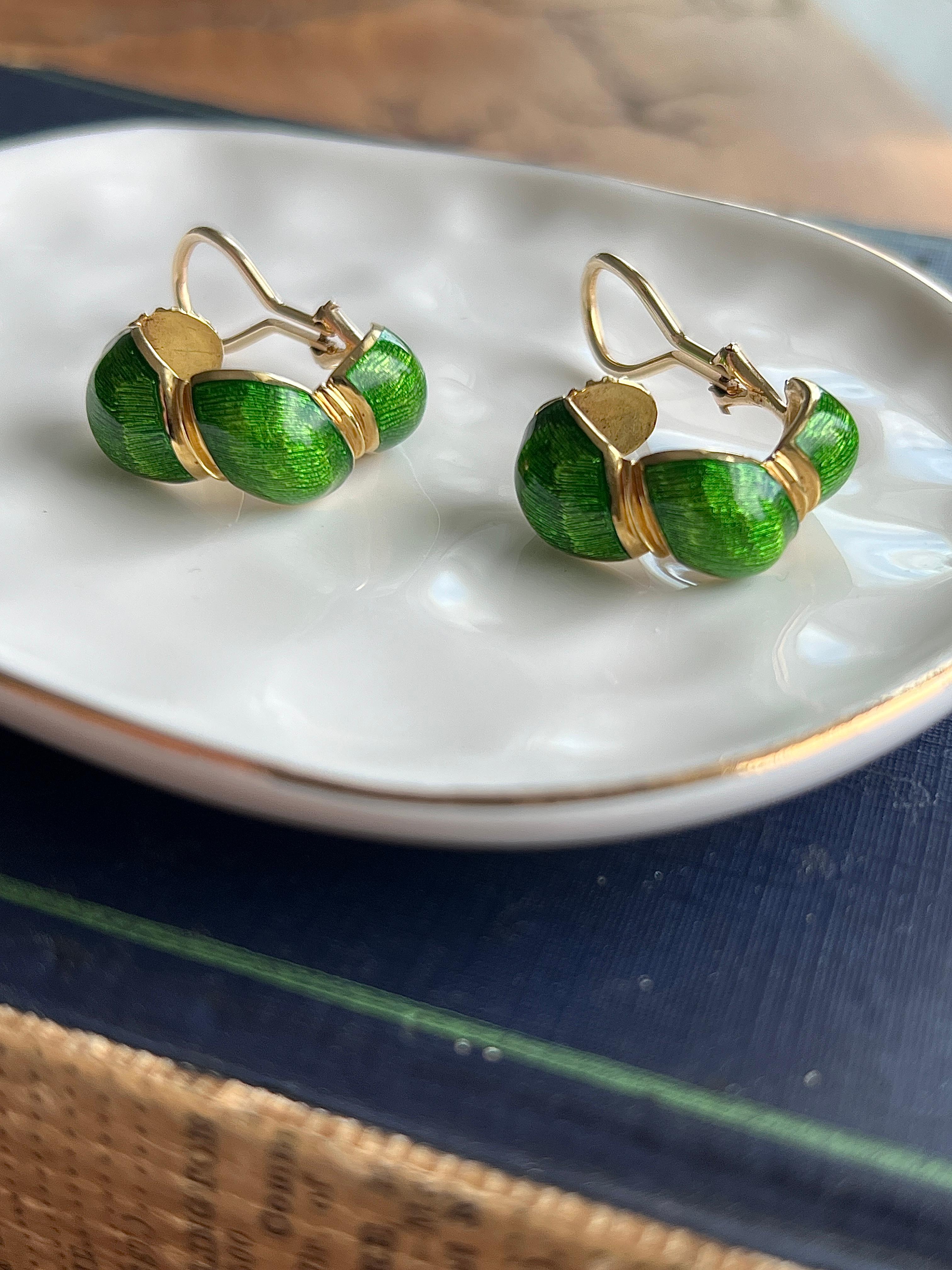 A striking pair of 1960s hoop earrings crafted in rich 18 karat yellow gold, these vintage beauties feature a vibrant green enamel design that adds a bold splash of color and character. The hoops measure approximately 1 inch in length, 0.75 inches