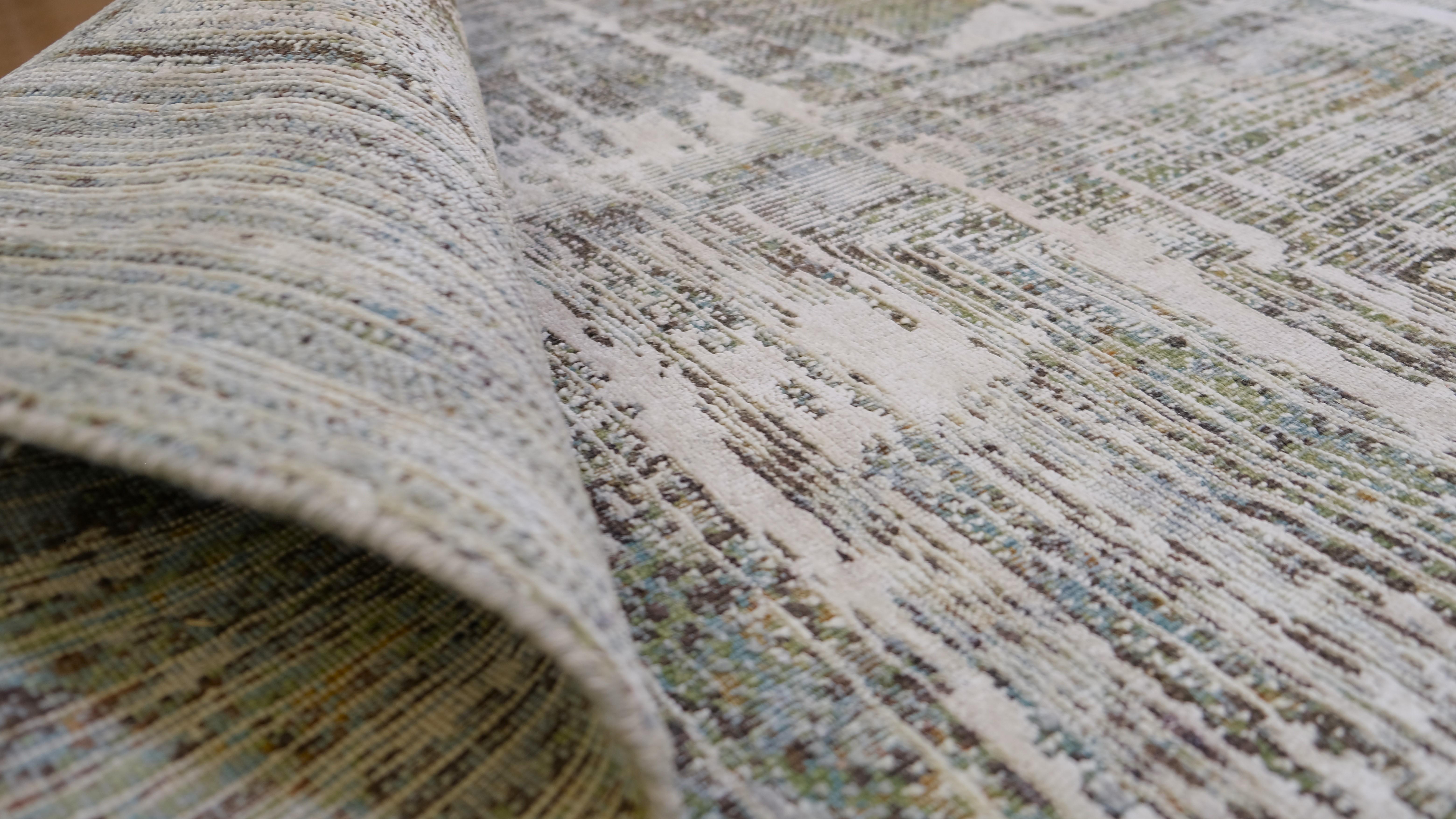 This stunning hand-knotted rug combines wool and silk to create a luxurious and contemporary masterpiece. Featuring a layered geometric design in a subtle palette of greens, brown and ivory tones, the rug offers a mesmerizing depth and texture that