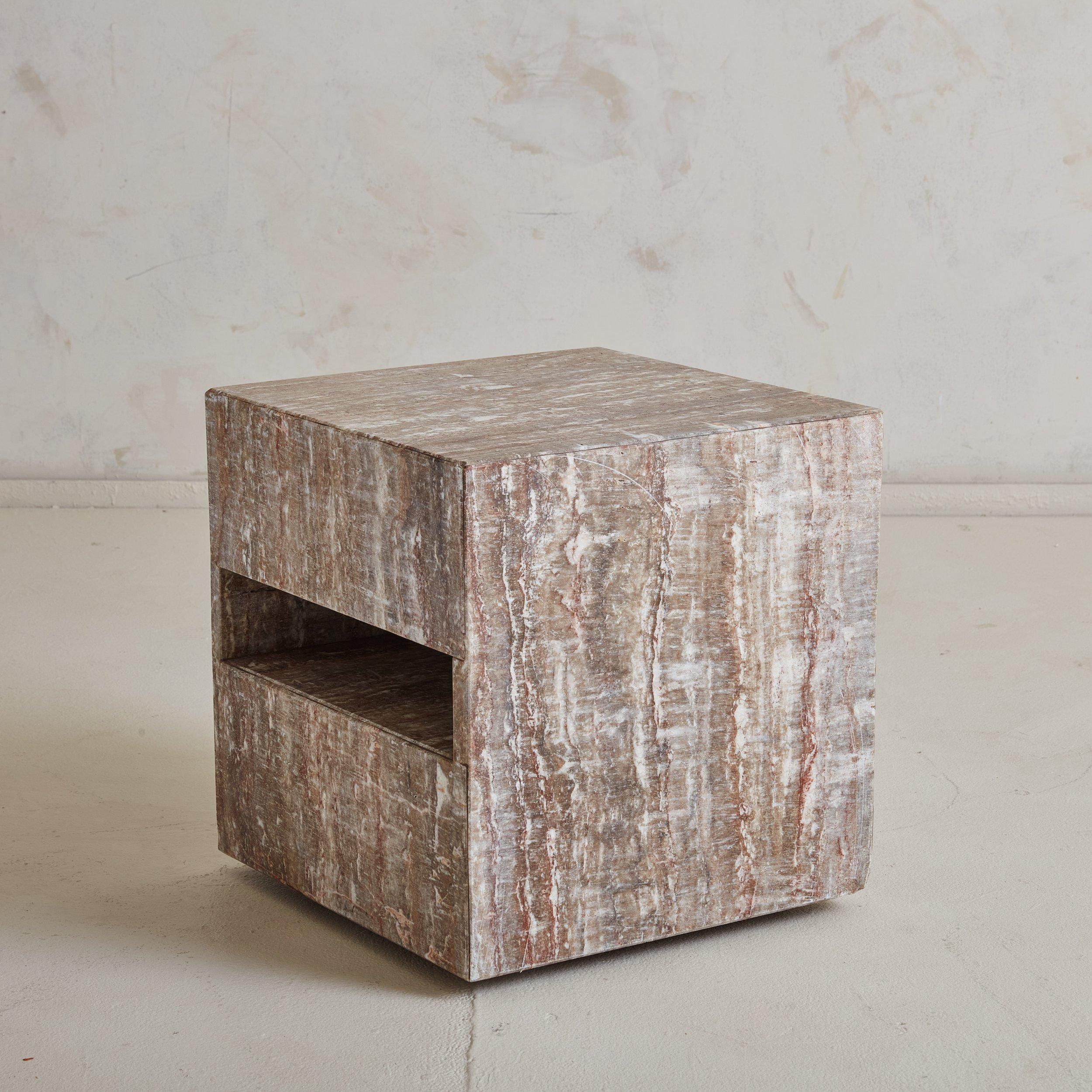 A 1970s beautifully veined grey marble side table with wheels. This Modern cubic side table features three rectangular cutouts perfect for displaying design books. The marble varies in hue, incorporating shades of grey, terracotta, and creamy white.