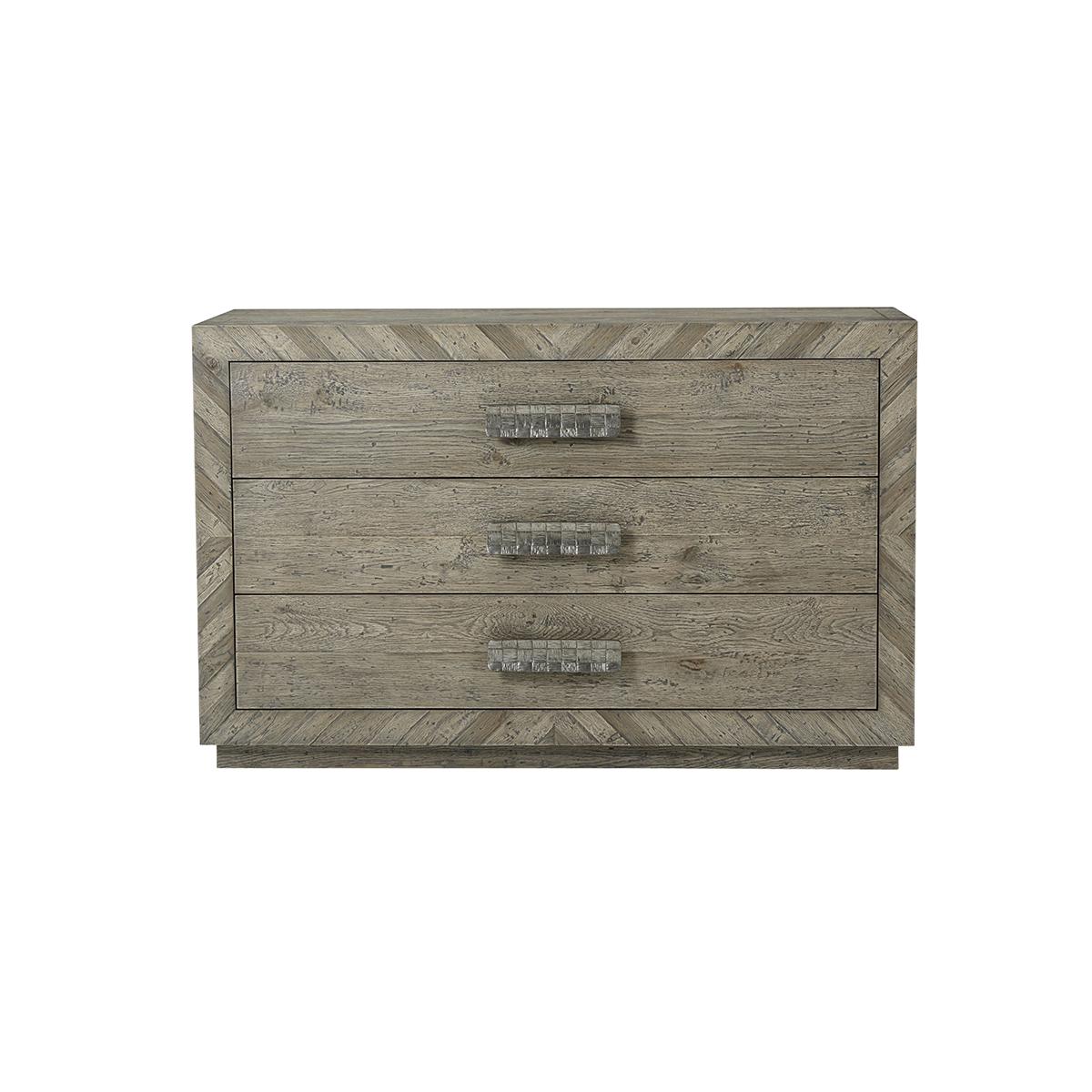 With three long drawers with a 'woven' cast vintage metal handle, a chevron parquetry inlaid frame and side panels also with vintage metal X details. In a greyed echo oak finish on a square plinth base.

Dimensions: 54