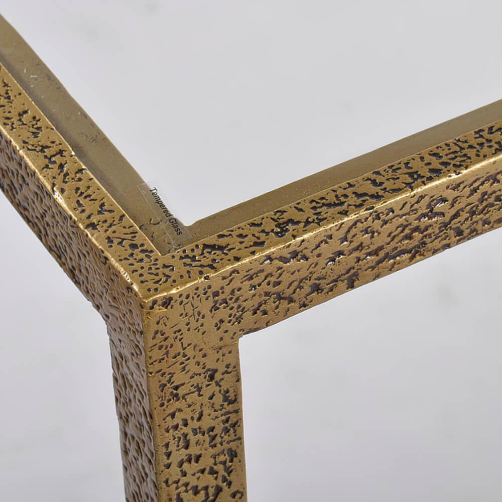 A modern hammered narrow rectangle console table, with clear tempered glass top and shelf, has a “gold leaf” finish on cast textured aluminum frame and tapered legs.

Dimensions: 62