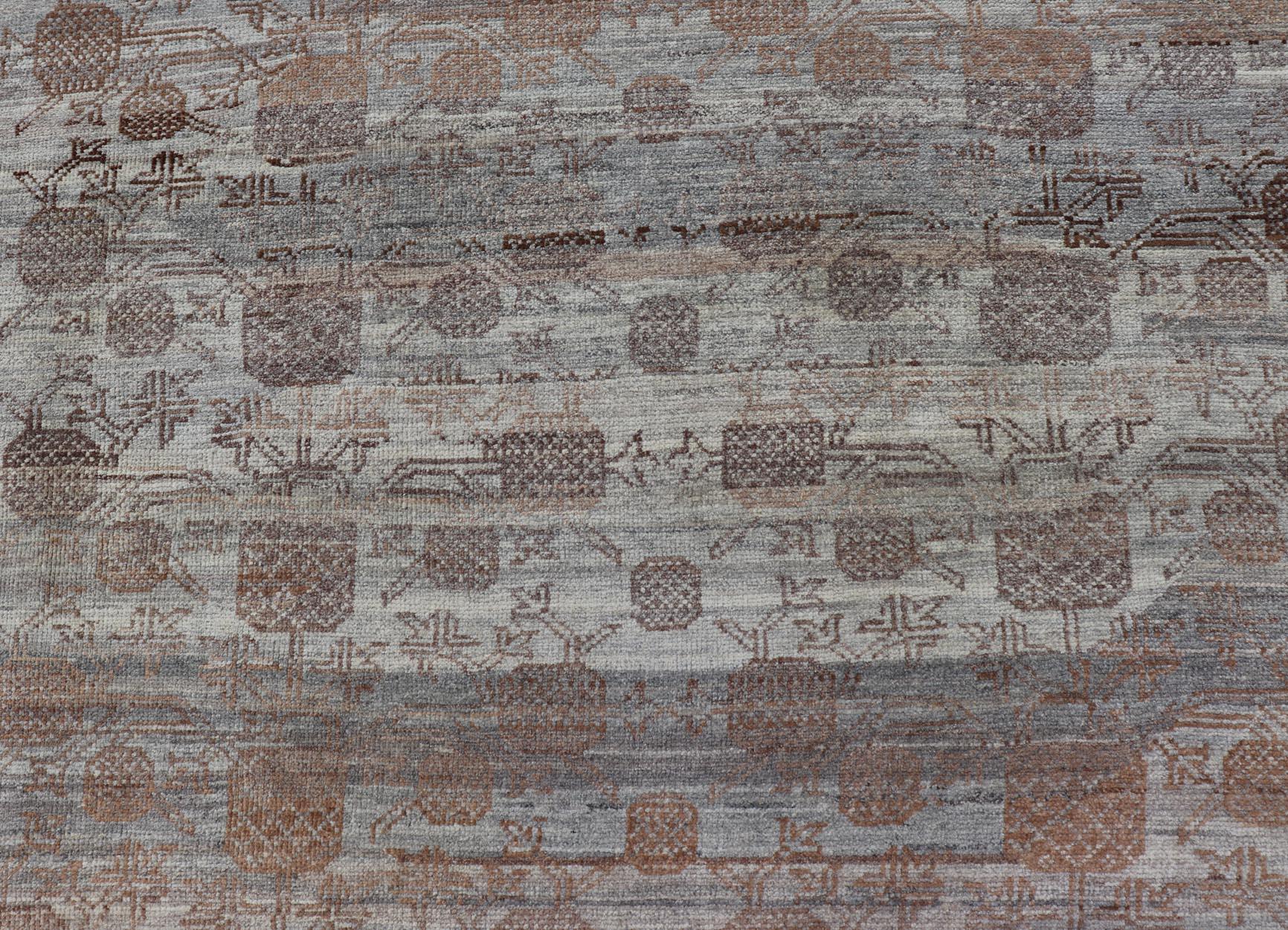 This modern casual tribal rug has been hand-knotted. The rug features a modern sub-geometric pomegranate design and is enclosed within a complementary, multi-tiered border, rendered in brown and gray tones; this rug is a superb fit for a variety of