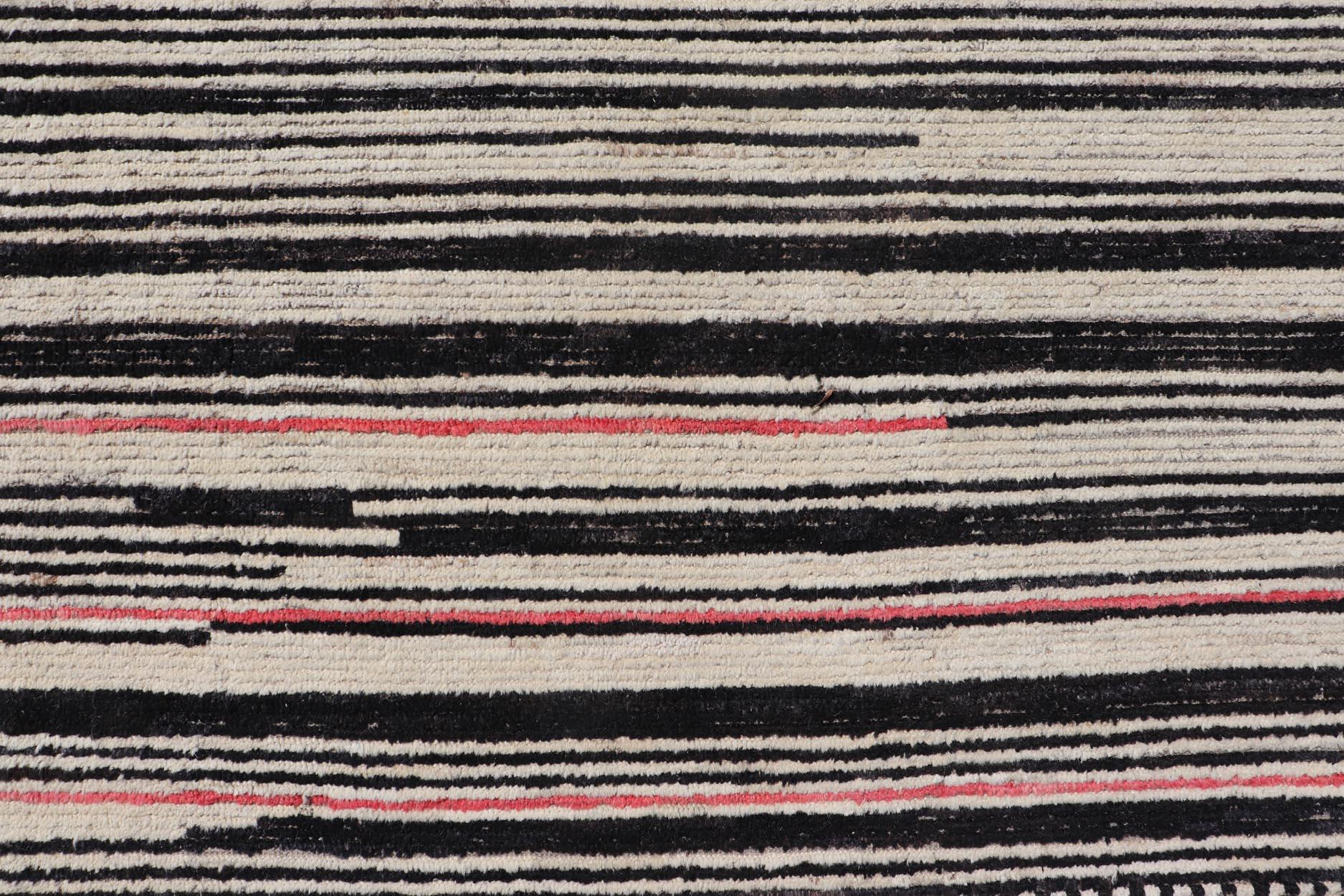 Ce tapis tribal moderne et décontracté a été noué à la main. Le tapis présente un design linéaire abstrait sous-géométrique moderne, rendu en noir et ivoire ; ce qui fait que ce tapis s'adapte parfaitement à une variété d'intérieurs classiques,