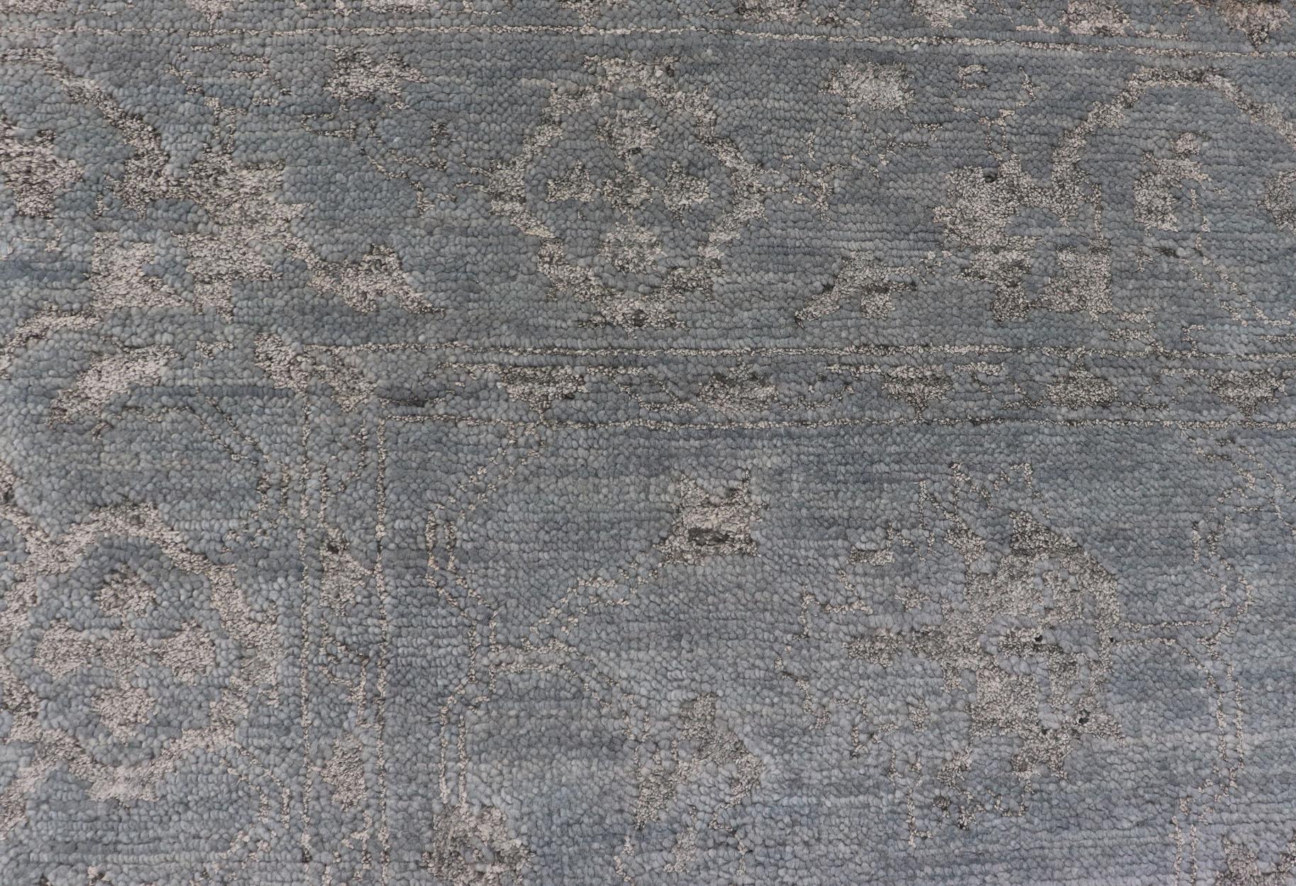 Medidas: 6' x 9'
Alfombra moderna anudada a mano en lana con diseño floral en azul y gris

Esta moderna alfombra india, anudada a mano en lana, presenta un diseño floral subgeométrico en tonos azules y grises. Un borde complementario de varios