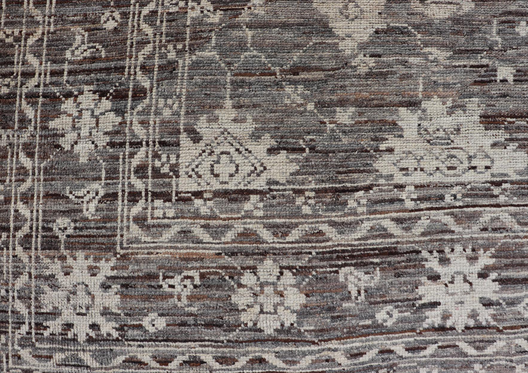 Dieser moderne, legere Teppich ist handgeknüpft. Der Teppich zeichnet sich durch ein modernes, subgeometrisches Oushak-Design mit verschiedenen Motiven aus, das in erdigen und neutralen Tönen gehalten ist. Dadurch passt dieser Teppich hervorragend