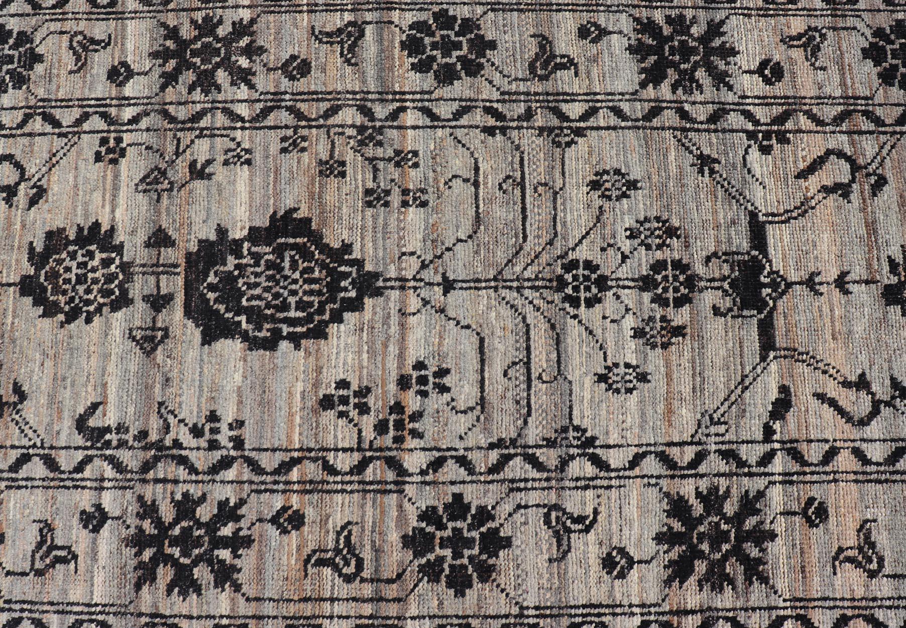This modern oushak designed tribal rug has been hand-knotted. The rug features a modern sub-geometric Oushak design, replete with various motifs in charcoal on an earthy tone background and enclosed within a complementary border; making this rug a