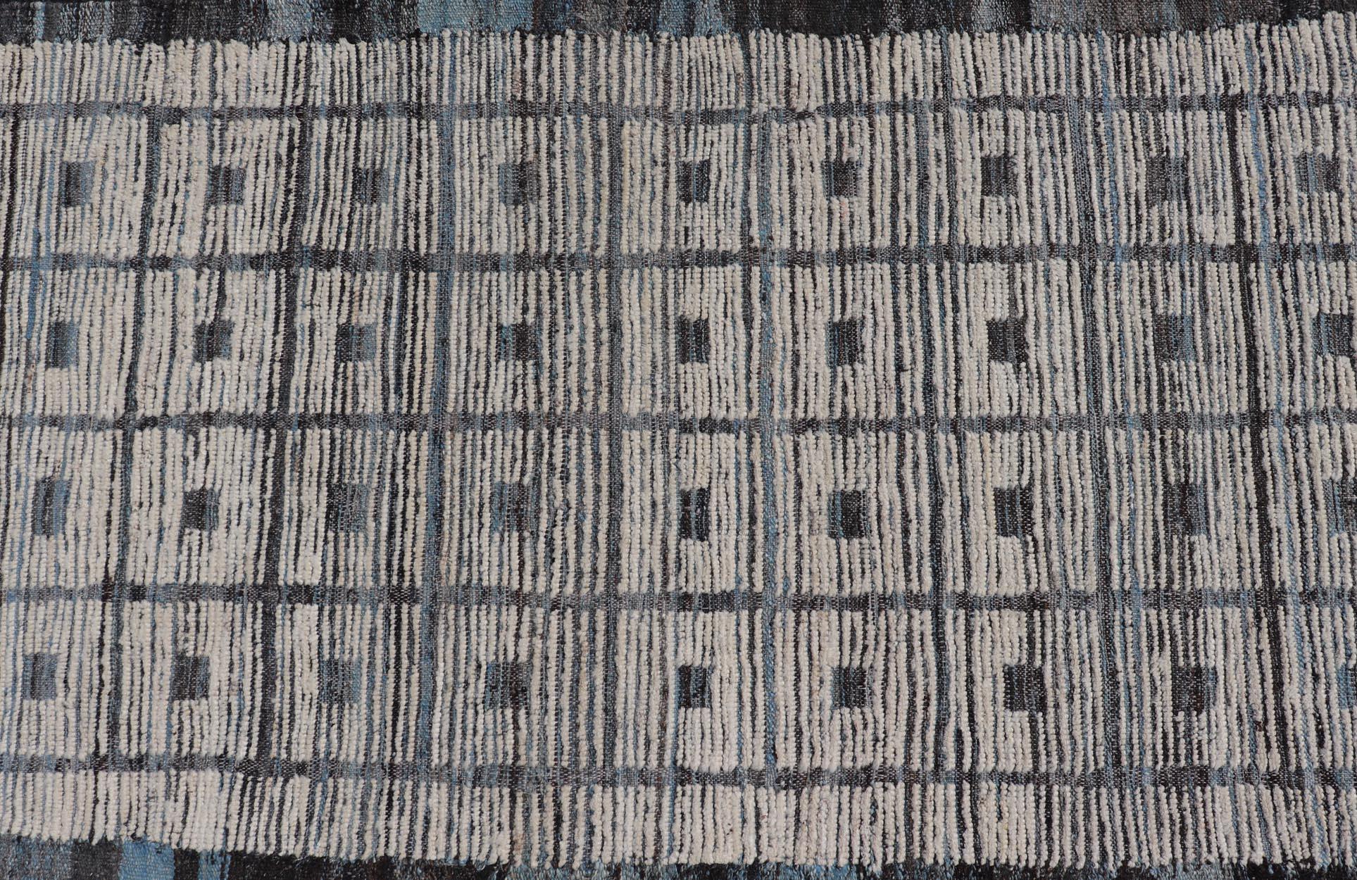 This modern casual tribal runner has been hand-knotted in wool. The runner features a modern all-over sub-geometric box design, rendered in blues, charcoals and ivory tones; making this rug a superb fit for a variety of classic, modern, casual and