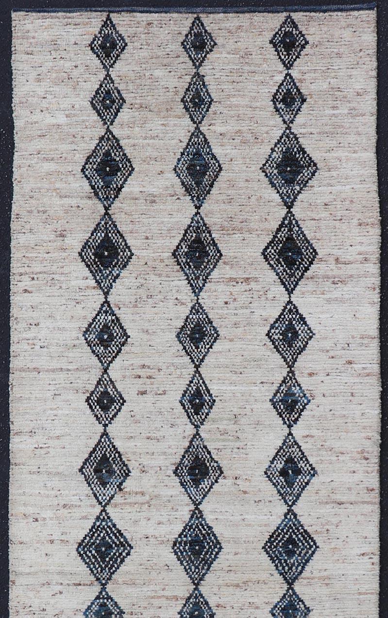 Alfombra de lana anudada a mano con diseño de rombos en azul y marfil. Keivan Woven Arts; alfombra SNK-2270, país de origen / tipo: Afganistán / Moderno Casual, hacia principios del siglo XXI.
Medidas: 3'1 x 10'1 
Este moderno y desenfadado corredor
