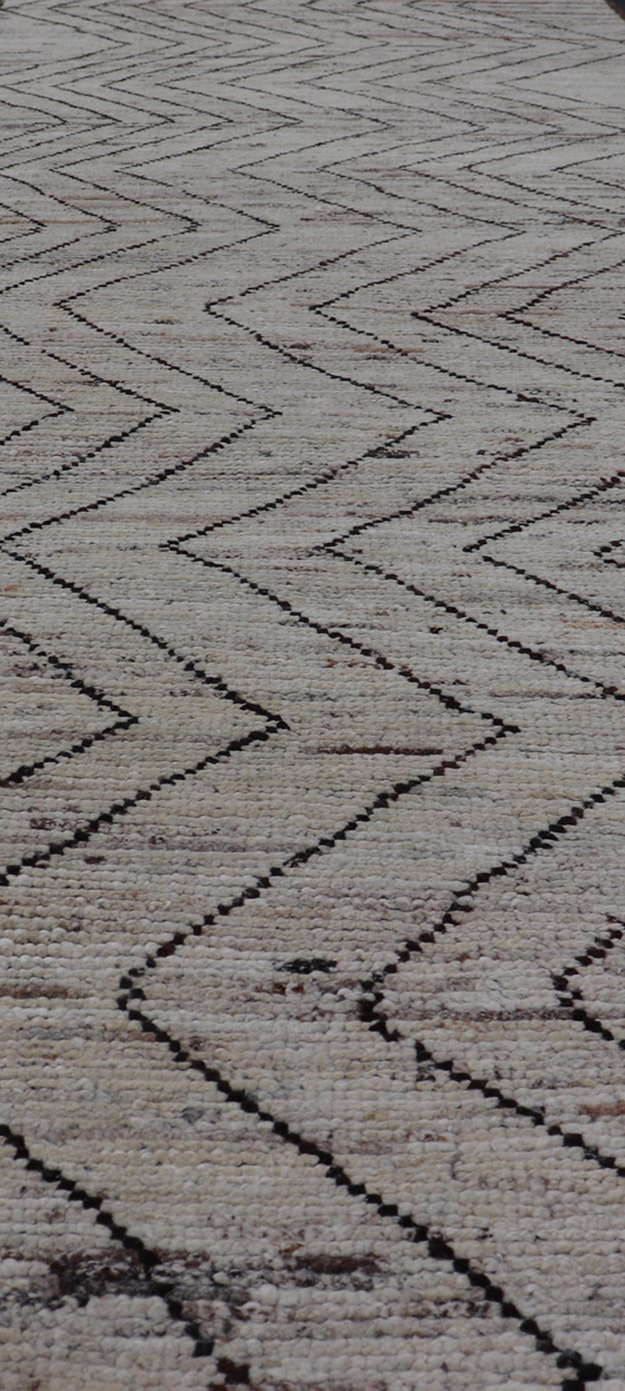 Dieser moderne, legere Läufer ist handgeknüpft. Der Teppich zeichnet sich durch ein modernes, subgeometrisches Zick-Zack-Muster aus, das in Schwarz und Erdtönen gehalten ist. Damit passt er hervorragend zu einer Vielzahl klassischer, moderner,