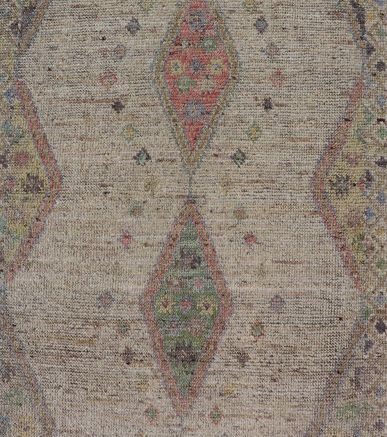 Dieser moderne, lässige Stammesteppich wurde aus Wolle handgeknüpft. Der Teppich zeichnet sich durch ein modernes, subgeometrisches, mehrfarbiges Rautenmuster aus, das von einer komplementären, mehrstufigen Bordüre umgeben ist, was diesen Teppich zu
