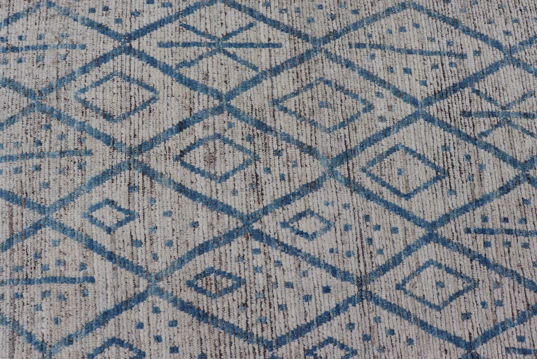 This modern casual tribal rug has been hand-knotted. The rug features a modern sub-geometric diamond design, replete with various motifs, rendered in blue and ivory; making this rug a superb fit for a variety of classic, modern, casual and