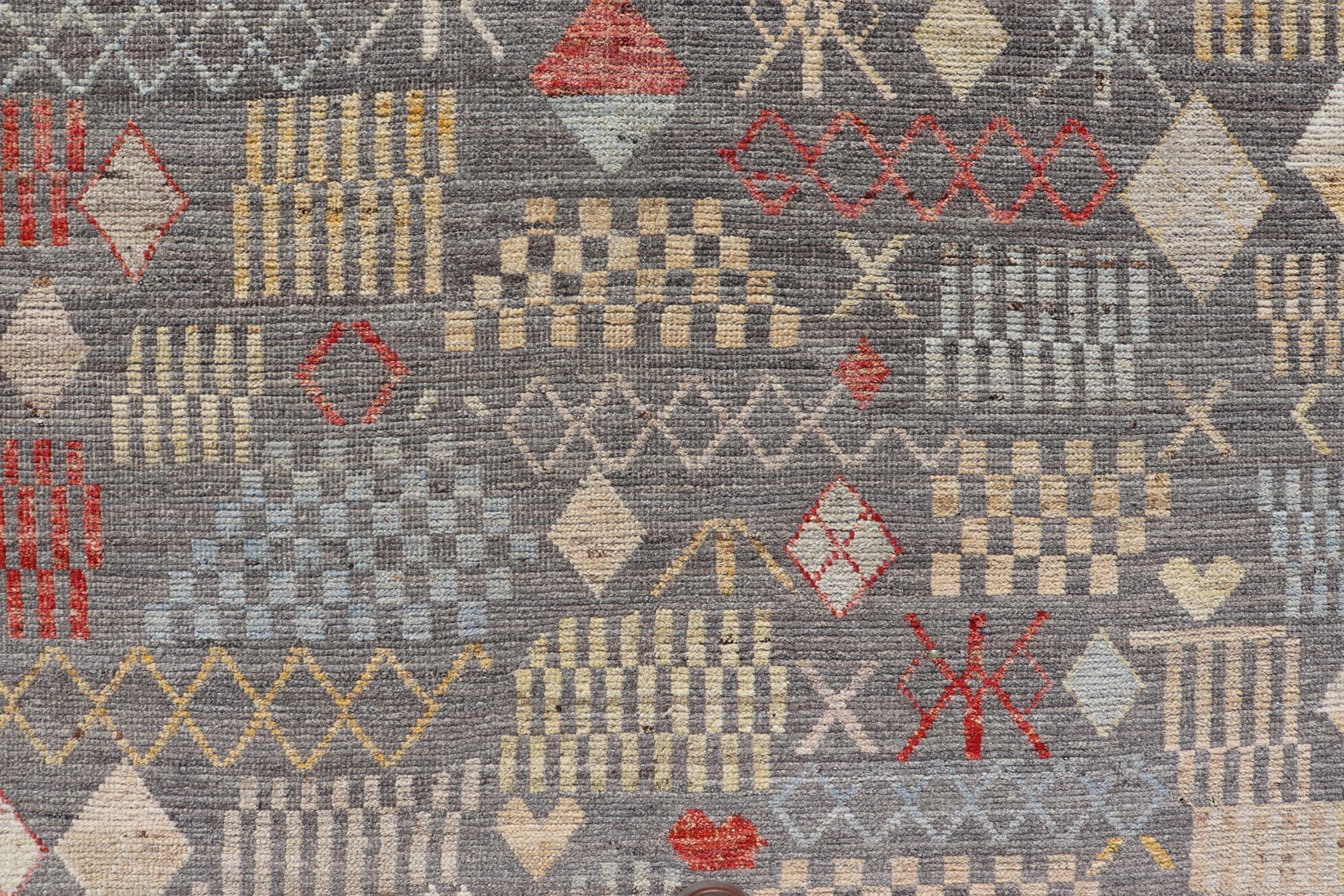 Dieser moderne, lässige Tribal-Teppich ist handgeknüpft. Der Teppich zeichnet sich durch ein modernes, subgeometrisches Allover-Muster aus, das mit verschiedenen mehrfarbigen Motiven angereichert ist. Dadurch passt dieser Teppich hervorragend zu