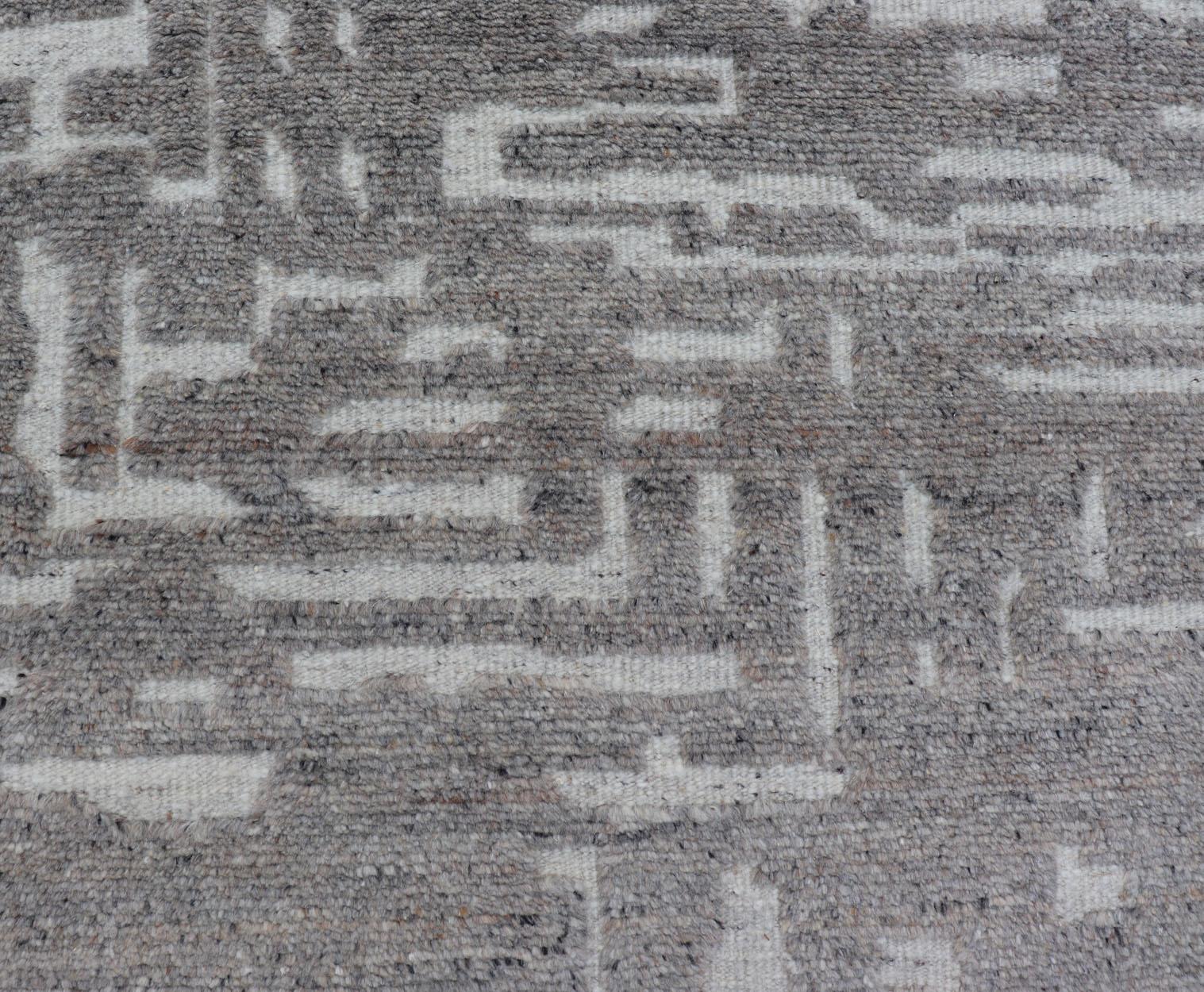 Mesures 5'8 x 8'5 

Le champ présente un motif abstrait subgéométrique qui couvre la totalité du tapis dans des tons de gris clair à Le motif est créé en abaissant les poils du gris clair et de la crème, ce qui donne au tapis une texture unique de
