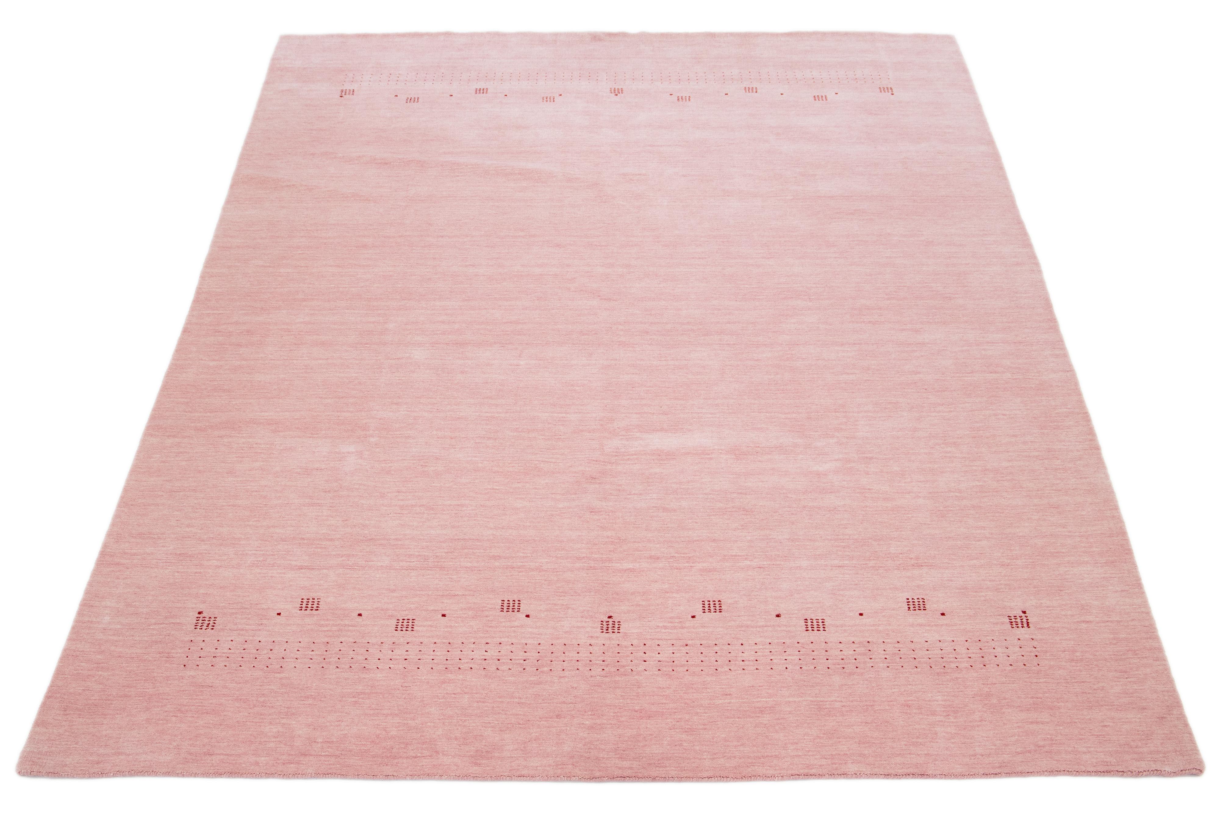Dieser moderne Gabbeh-Teppich ist handgewebt und weist ein modernes, minimalistisches geometrisches Muster auf. Die rosafarbene Basis ist mit roten Details akzentuiert.

Dieser Teppich misst 9' x 11'10