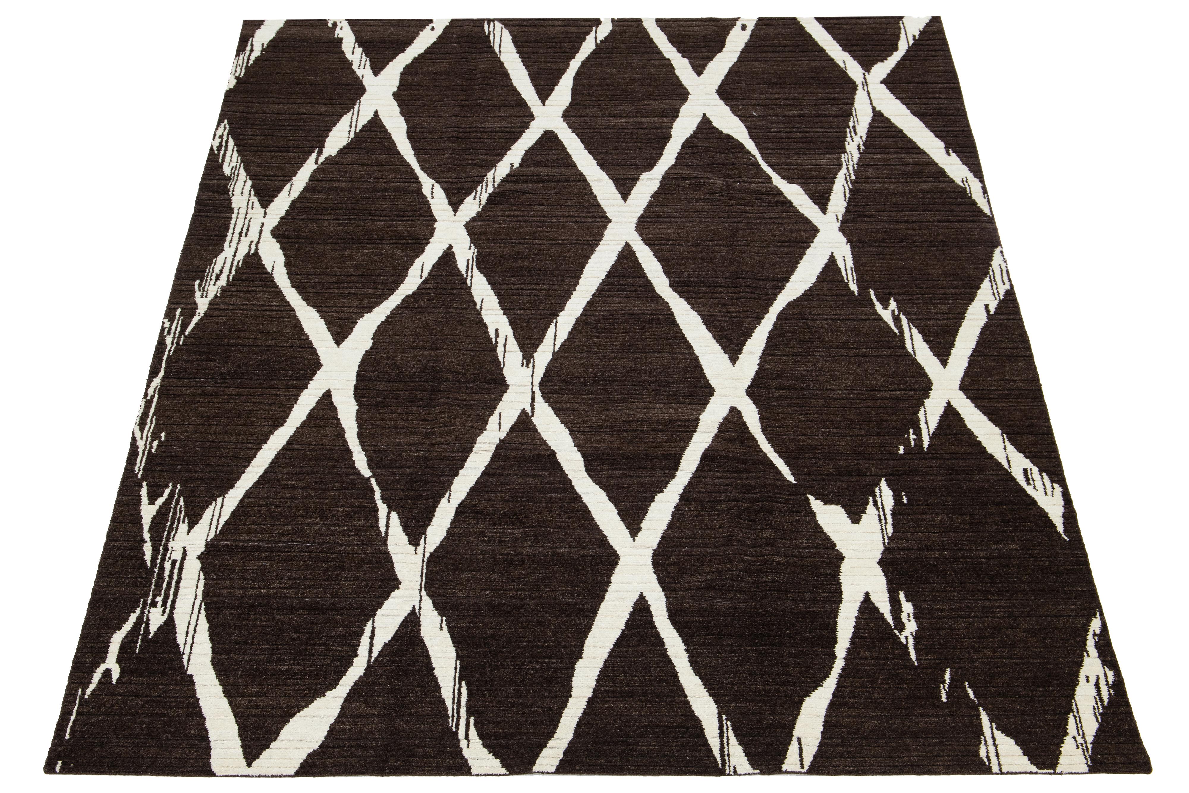 Dieser exquisite Teppich zeigt ein zeitgenössisches Design, das sorgfältig von Hand gewebt wurde und ein auffälliges geometrisches Muster in Beige auf einem satten braunen Grundmuster aufweist.

Dieser Teppich misst 9' x 12'.

