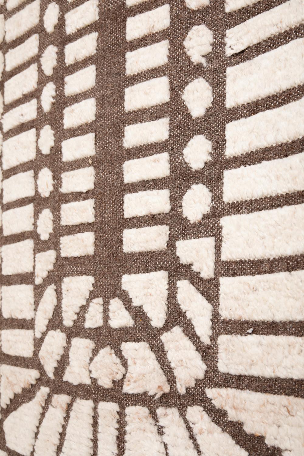 Ce tapis a été noué à la main de manière éthique dans les fils de laine mérinos les plus fins par des artisans du nord de l'Inde. La partie brune a une épaisseur de 6 mm et la partie blanche de 15 mm.
Chaque tapis est noué à la main avec des détails