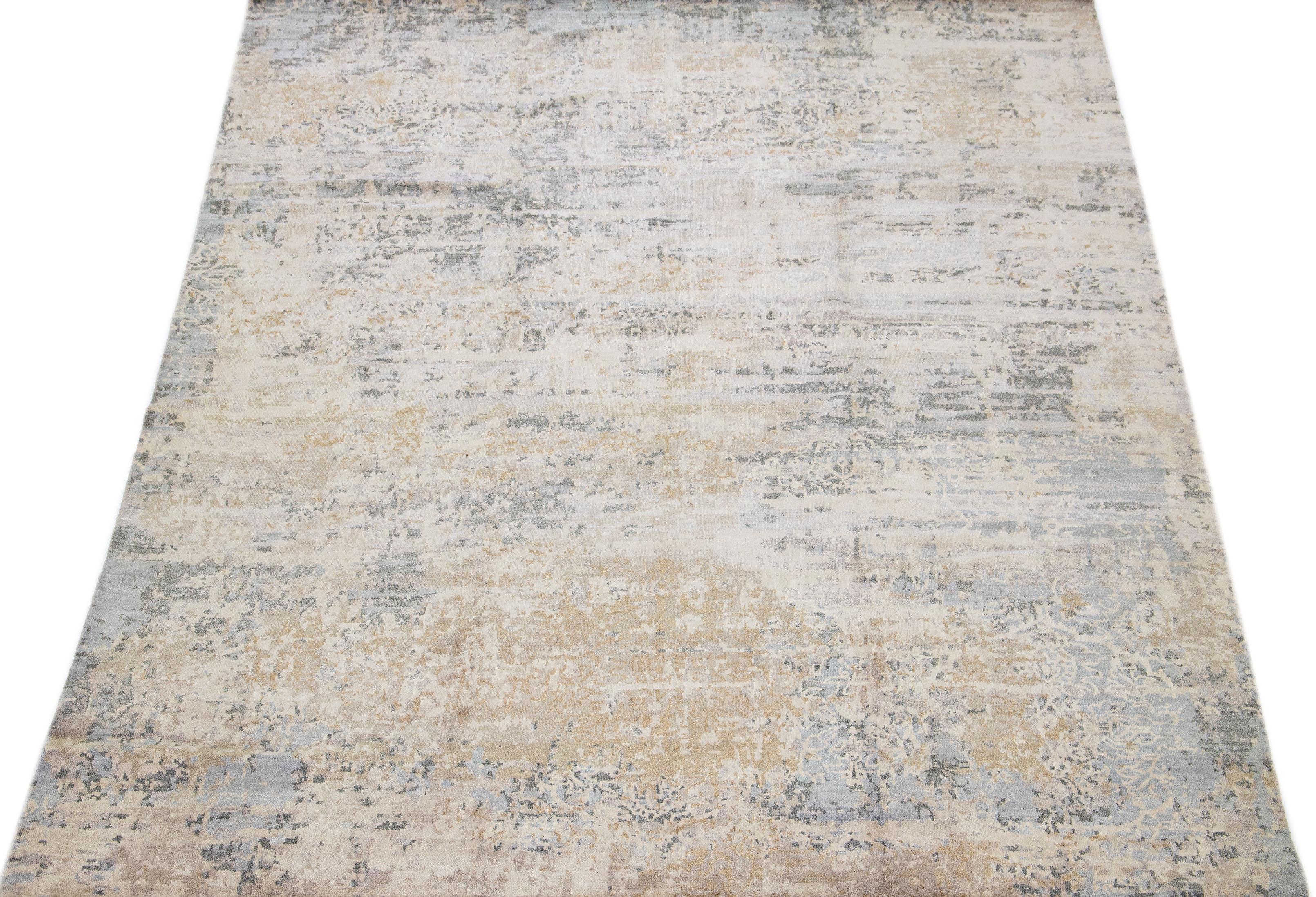 This rug is a beautiful blend of Indian wool and silk, boasting a beige field with a tasteful abstract pattern in shades of gray. The rug's meticulously crafted composition ensures durability and longevity, while its exquisite decorative design adds