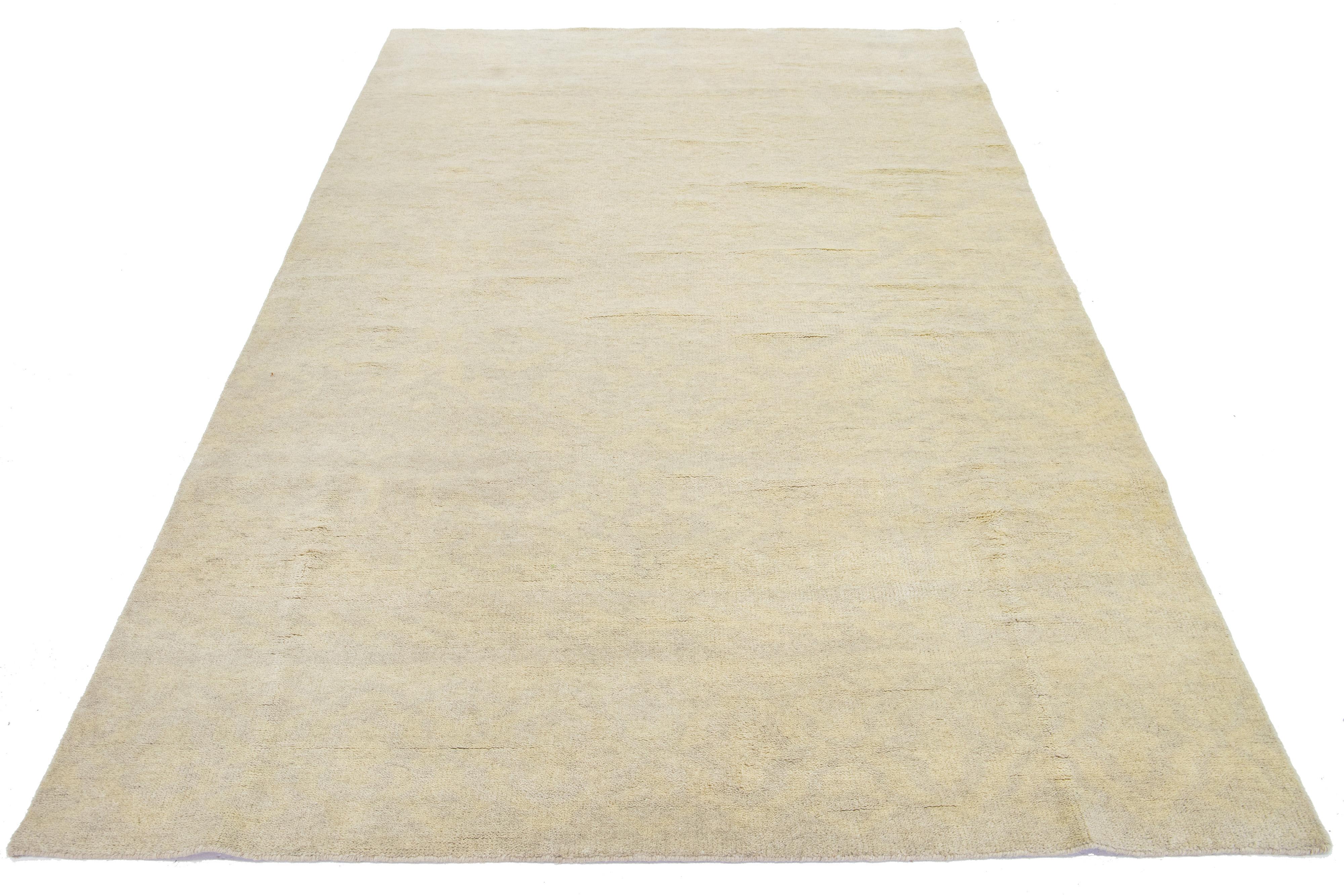 The contemporary Khotan wool rug from India. The design showcases a deep beige base with intricate cream-colored trellis patterns. These include eye-catching geometric elements.

This rug measures 6'6
