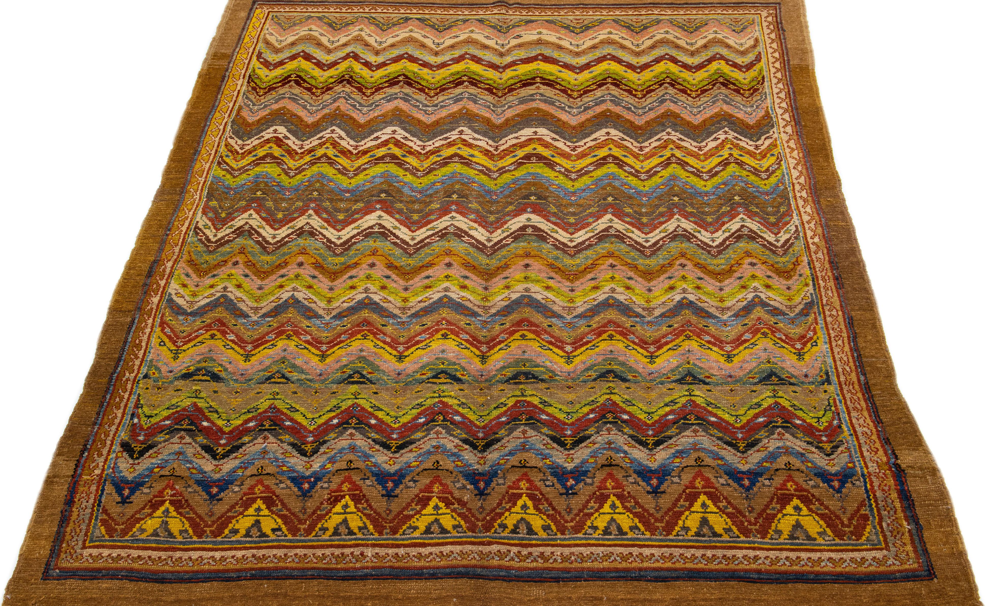 Beautiful modern hand knotted wool rug with a brown color field. This Revival Collection rug has bright accents all-over a gorgeous geometric design with an Antique look. 

This rug measures 6'7
