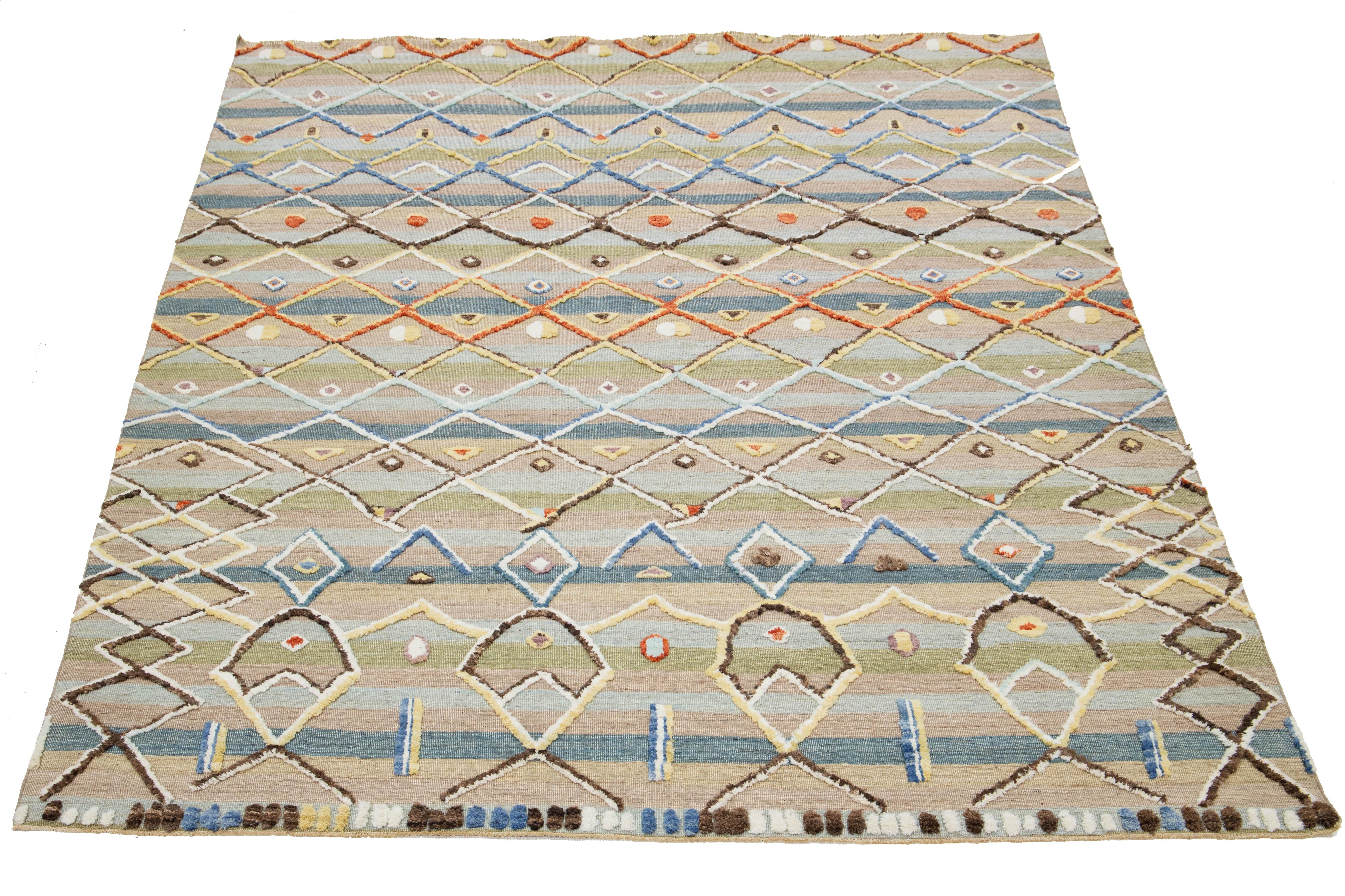 Voici un exquis tapis de laine contemporain de style marocain, fabriqué à la main. Ce tapis, qui présente un mélange harmonieux de teintes beiges, vertes et bleues, allie admirablement l'artisanat traditionnel à l'esthétique moderne. Les motifs